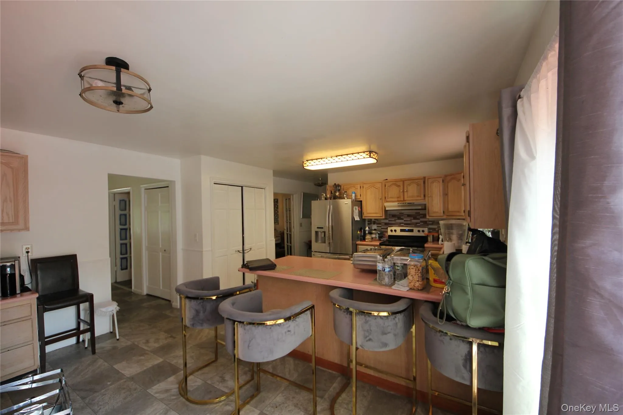 Kitchen featuring an island with countertop, natural wood cabinetry, stainless steel appliances, and a tile backsplash Kitchen featuring an island with countertop, natural wood cabinetry, stainless steel appliances, and a tile backsplash