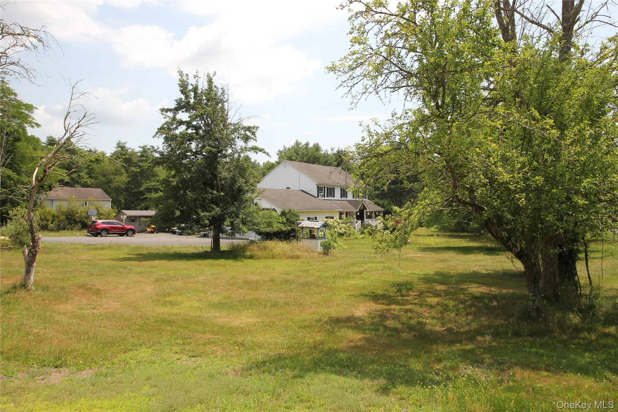 Expansive grassy area featuring mature trees and a two-story residence with white siding Expansive grassy area featuring mature trees and a two-story residence with white siding