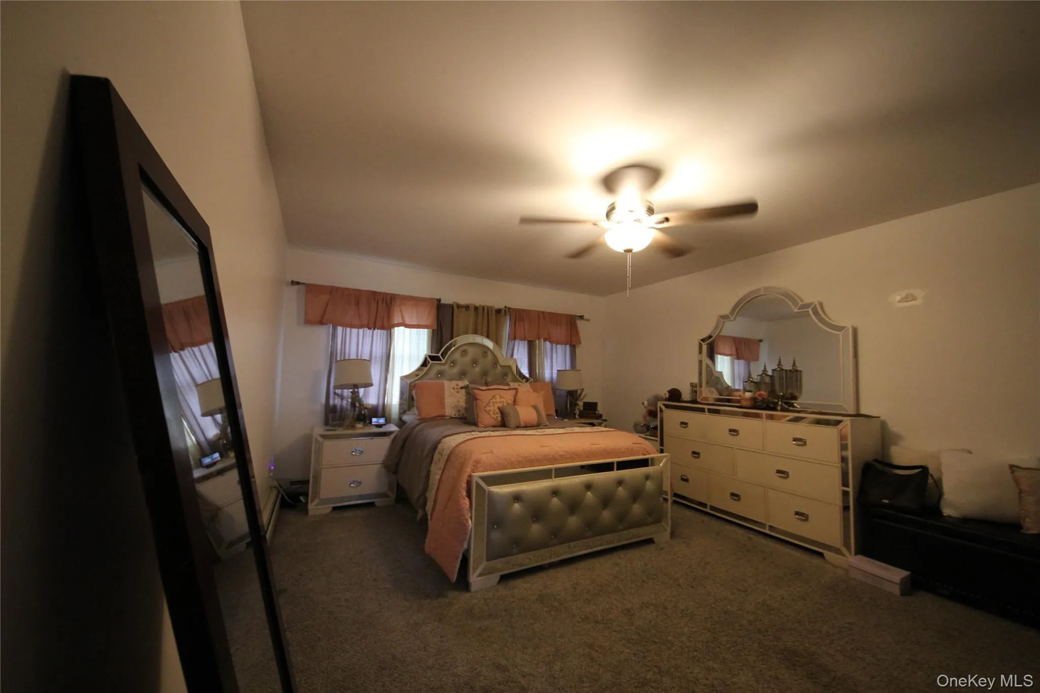 Carpeted room featuring a ceiling fan with integrated lighting, window treatments, and white walls Carpeted room featuring a ceiling fan with integrated lighting, window treatments, and white walls