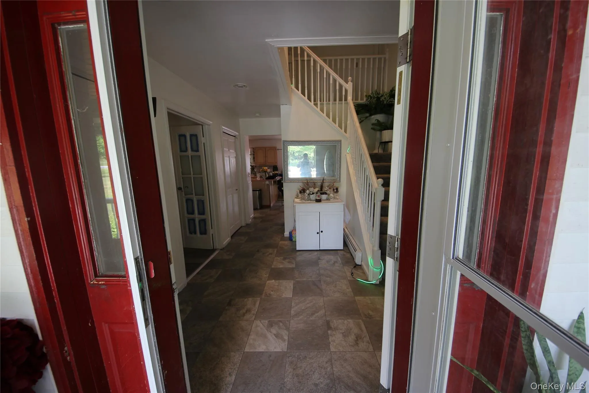 Entry foyer featuring tile flooring, a staircase with white railings, and a console table with built-in storage Entry foyer featuring tile flooring, a staircase with white railings, and a console table with built-in storage