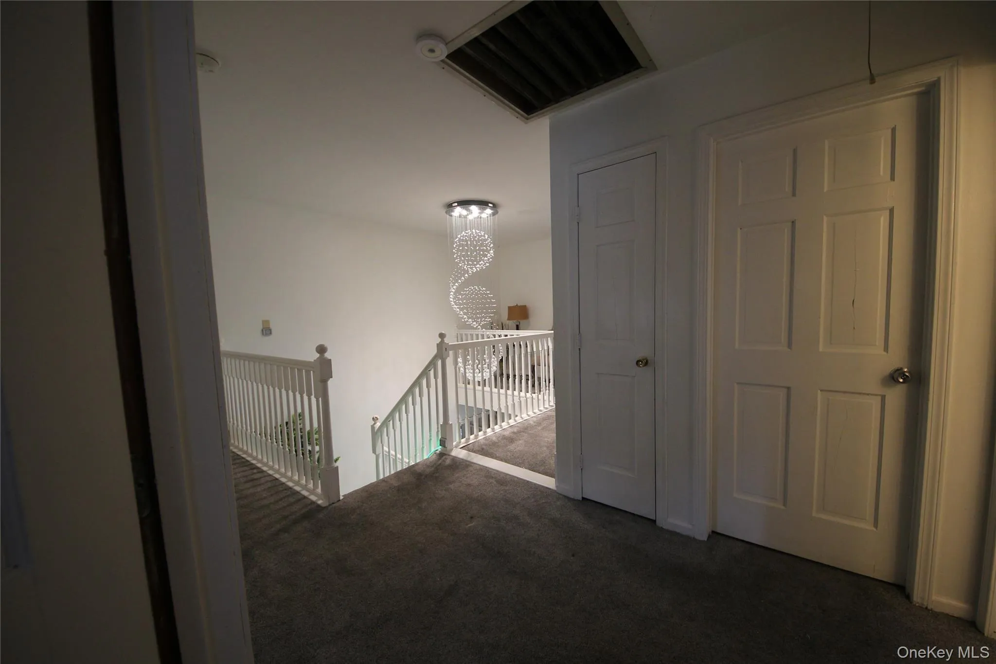Second-story hallway featuring gray carpeting and white paneled doors Second-story hallway featuring gray carpeting and white paneled doors