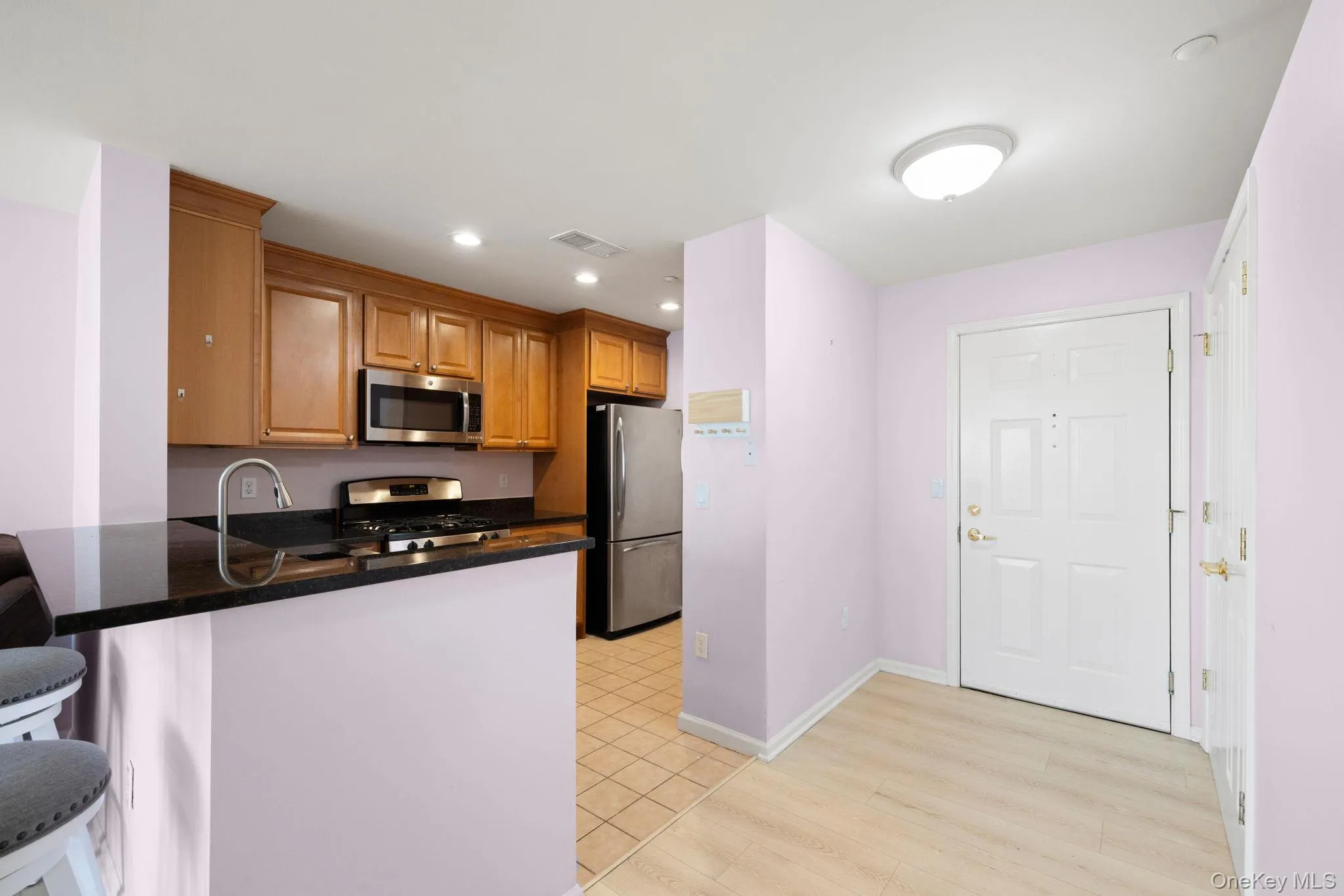 Kitchen area featuring wood cabinetry, stainless steel appliances, and a black countertop with an integrated sink Kitchen area featuring wood cabinetry, stainless steel appliances, and a black countertop with an integrated sink