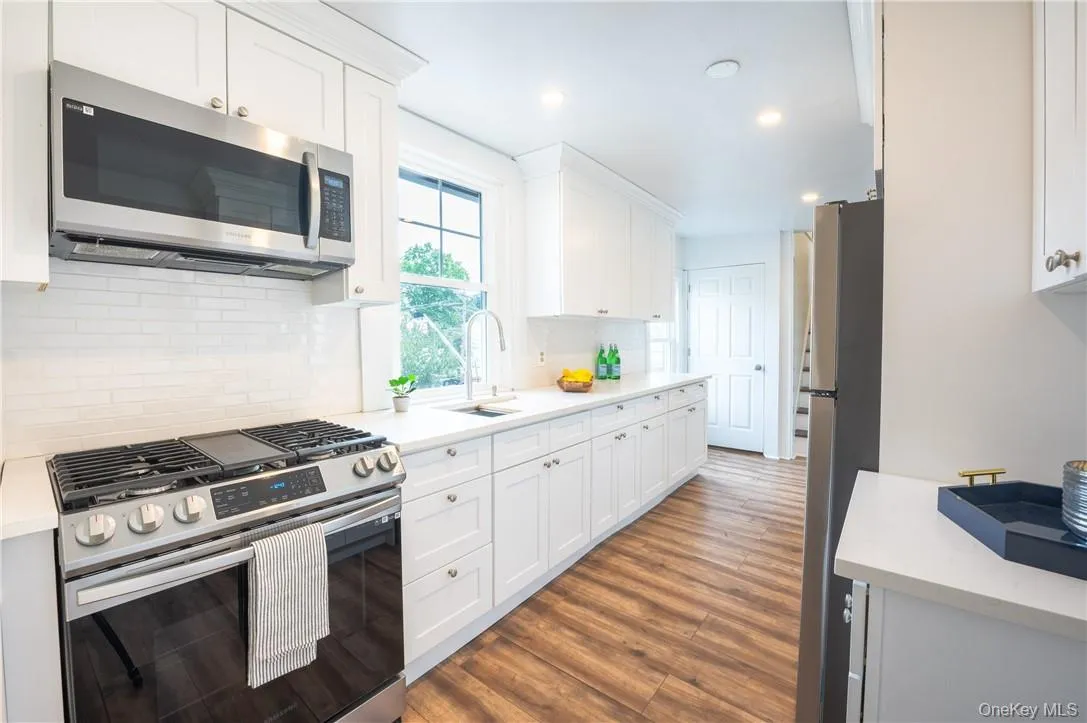 Kitchen featuring white cabinets, stainless steel appliances, sink and tasteful backsplash Kitchen featuring white cabinets, stainless steel appliances, sink and tasteful backsplash