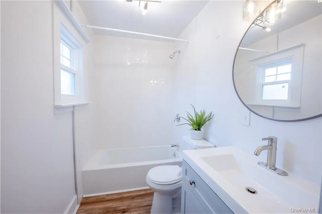 Full bathroom with wood-type flooring, toilet, vanity, and a healthy amount of sunlight Full bathroom with wood-type flooring, toilet, vanity, and a healthy amount of sunlight