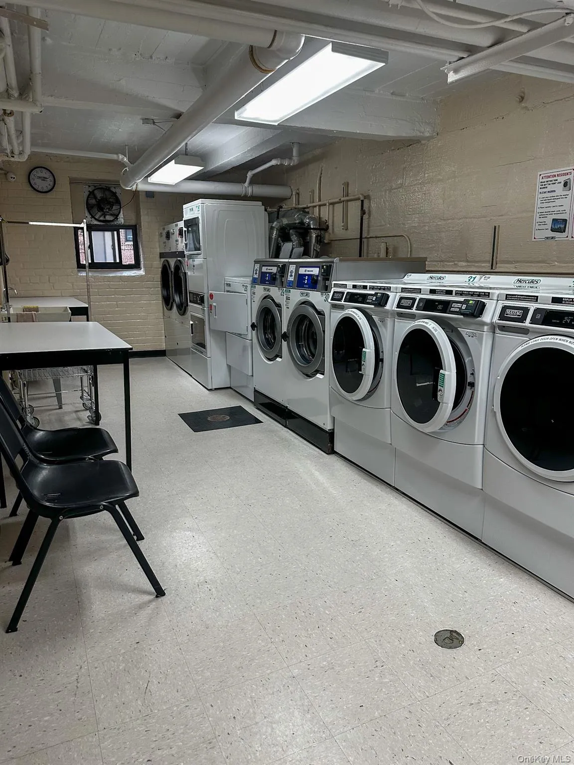 Community laundry facility featuring multiple front-loading washers and dryers, and ample overhead lighting Community laundry facility featuring multiple front-loading washers and dryers, and ample overhead lighting