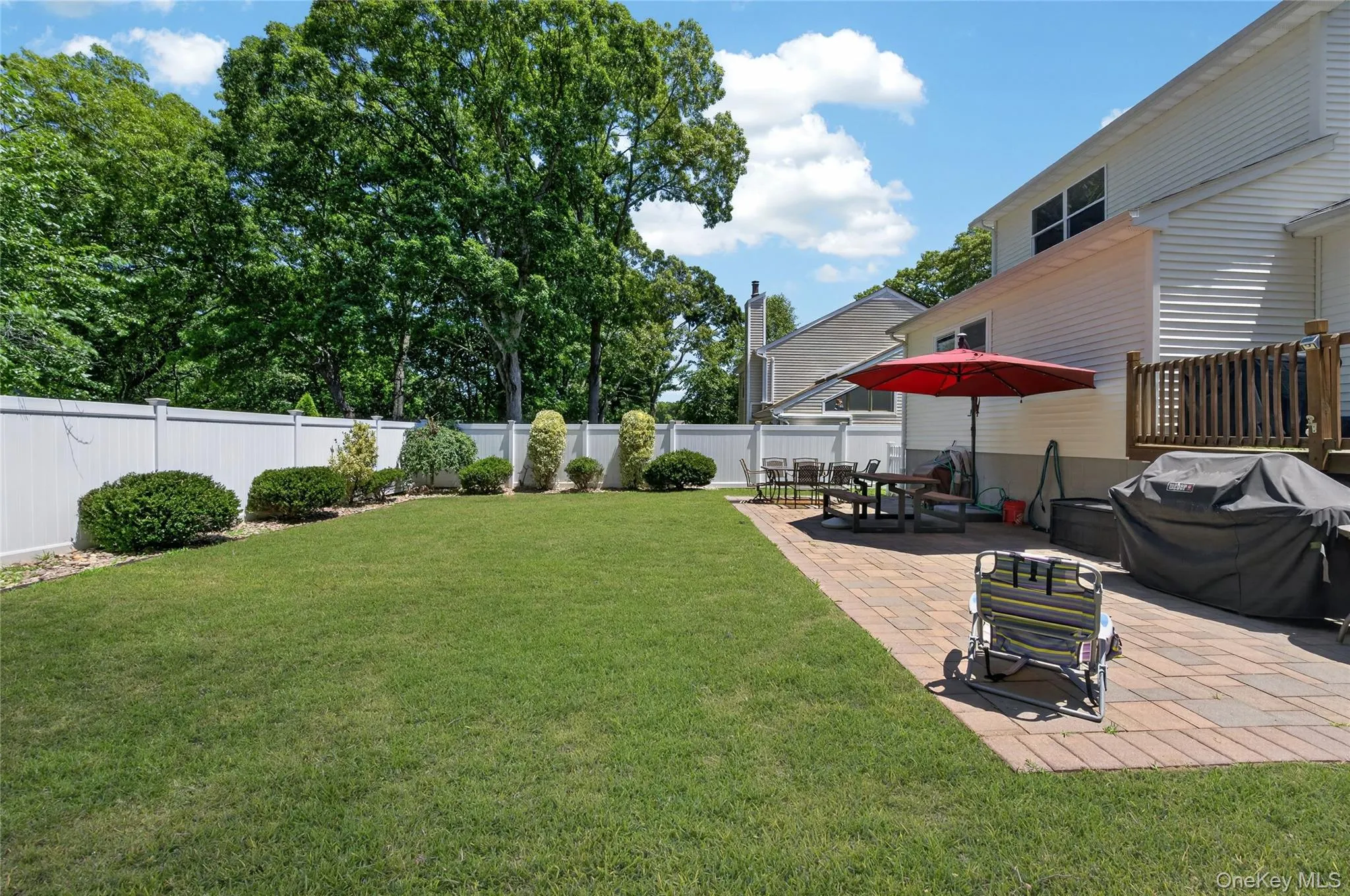 Expansive green lawn bordered by a white privacy fence and mature landscaping Expansive green lawn bordered by a white privacy fence and mature landscaping