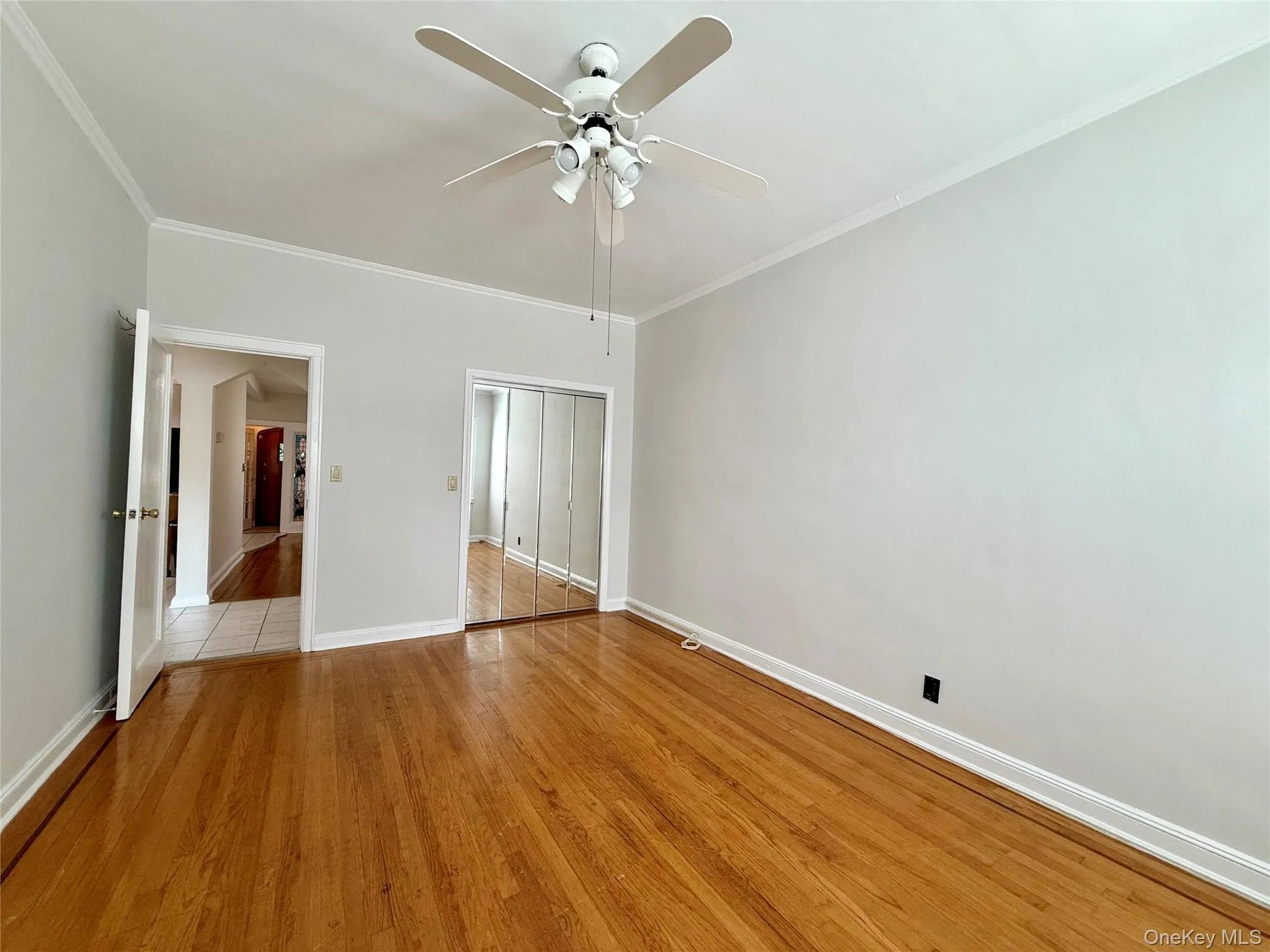 Hardwood flooring throughout, crown molding, ceiling fan with integrated lighting, and mirrored closet doors Hardwood flooring throughout, crown molding, ceiling fan with integrated lighting, and mirrored closet doors