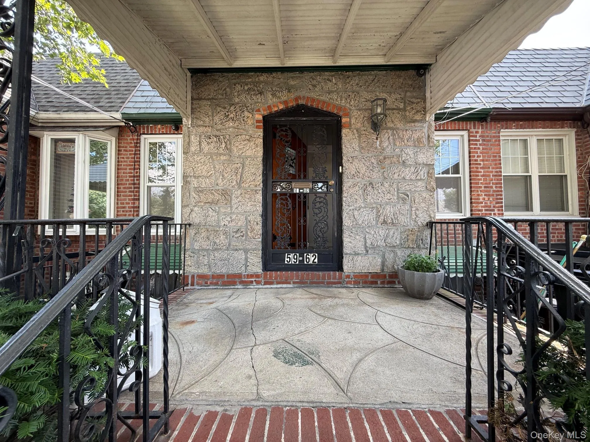 Porch entrance featuring a stone facade, brick details, an arched doorway, and wrought iron railings. Porch entrance featuring a stone facade, brick details, an arched doorway, and wrought iron railings.