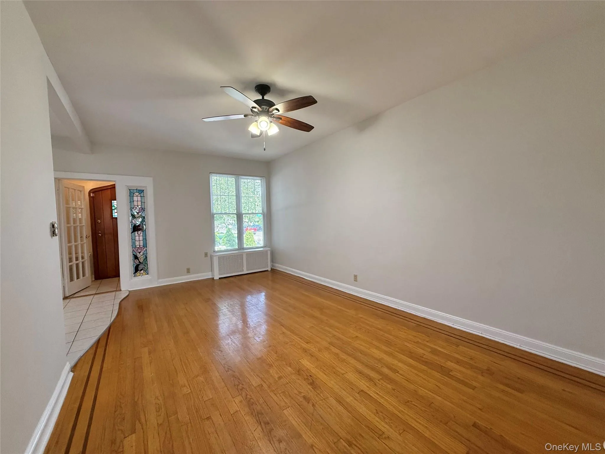 Large living room with double panel window, ceiling fan and light, beautiful hardwood floors Large living room with double panel window, ceiling fan and light, beautiful hardwood floors