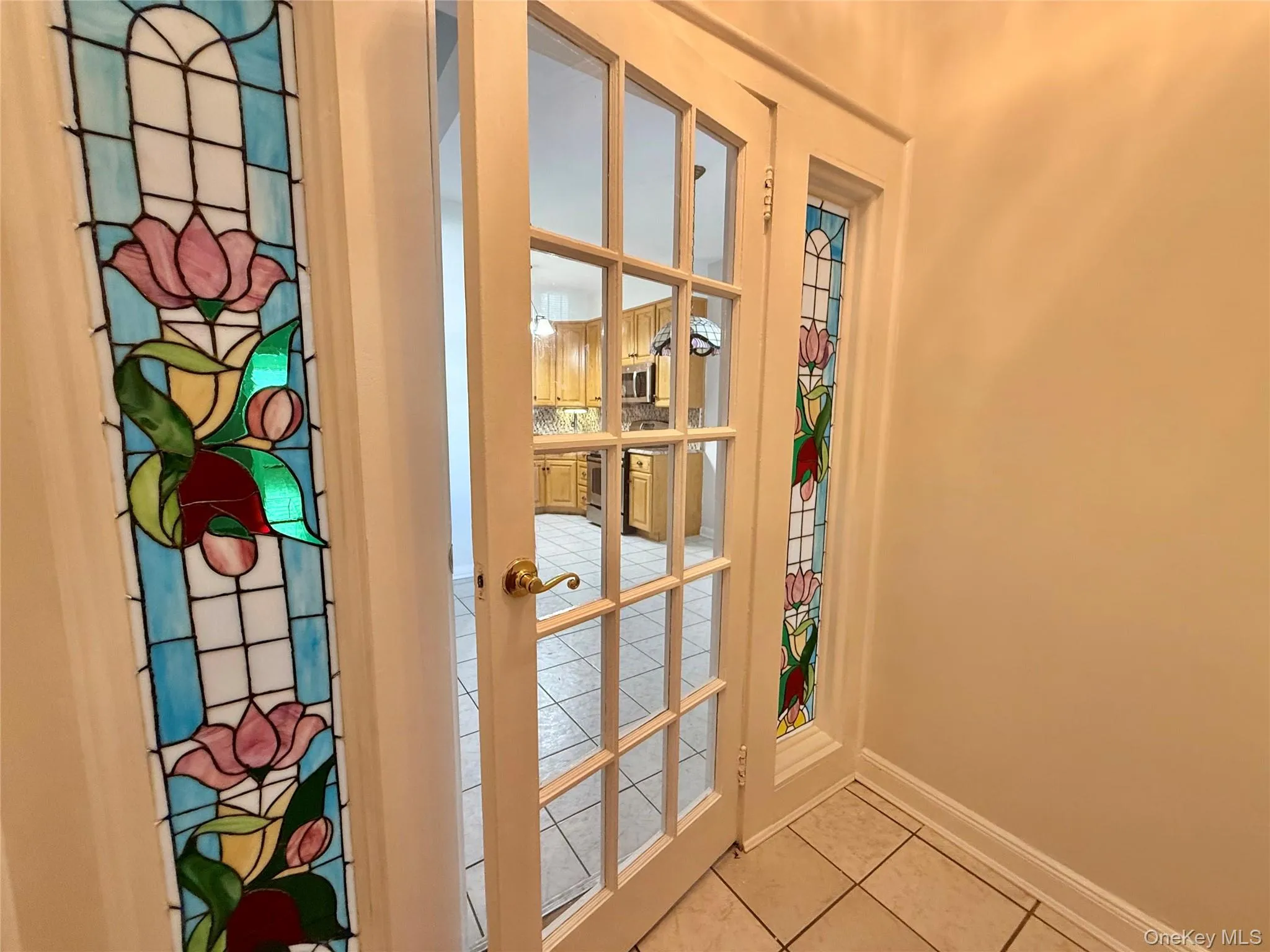 Entrance foyer with large glass stained glass panel next to a french glass door. Entrance foyer with large glass stained glass panel next to a french glass door.