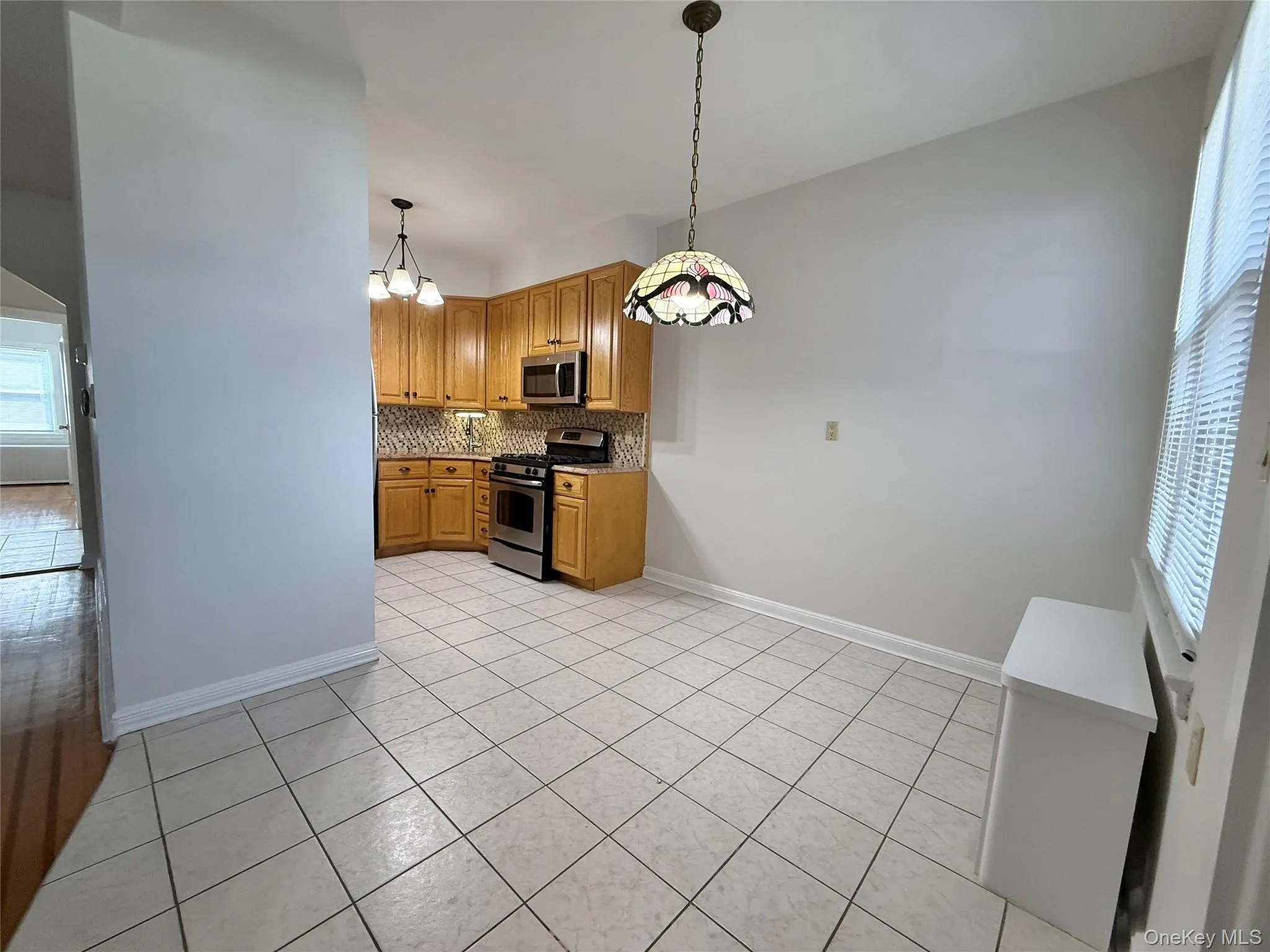 Dining area with tiled floors, glass tiffany style lamp, double panel window, open to the kitchen. Dining area with tiled floors, glass tiffany style lamp, double panel window, open to the kitchen.