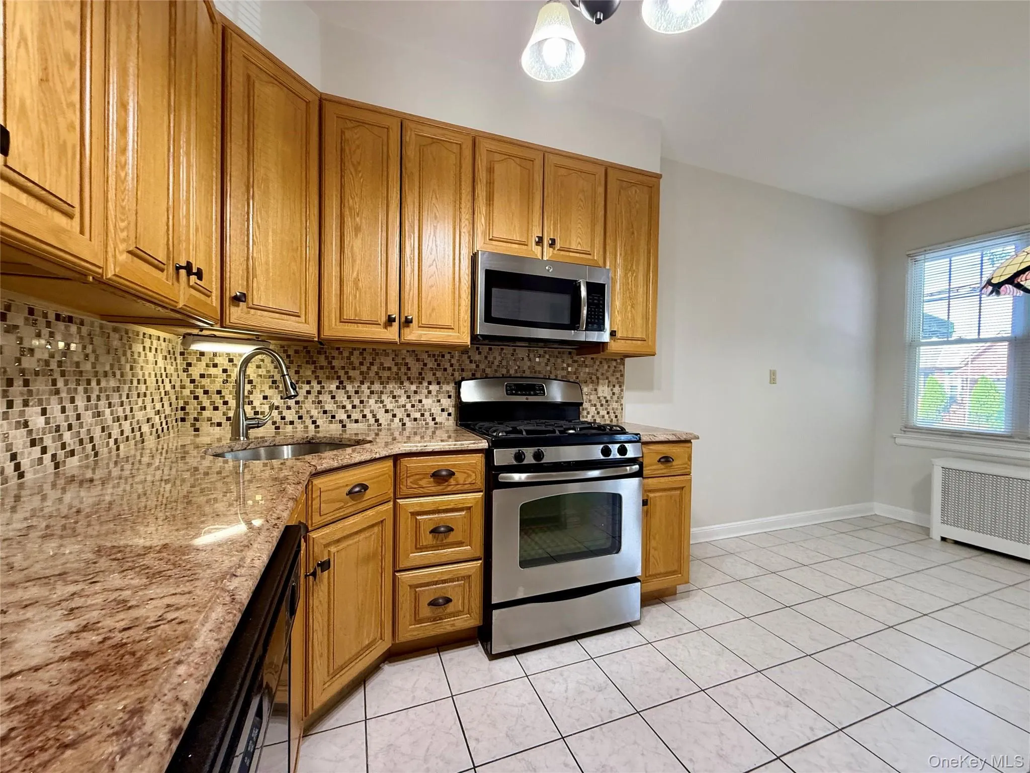 Kitchen featuring wood cabinetry with dark hardware, a mosaic tile backsplash, and a stainless steel appliance suite Kitchen featuring wood cabinetry with dark hardware, a mosaic tile backsplash, and a stainless steel appliance suite