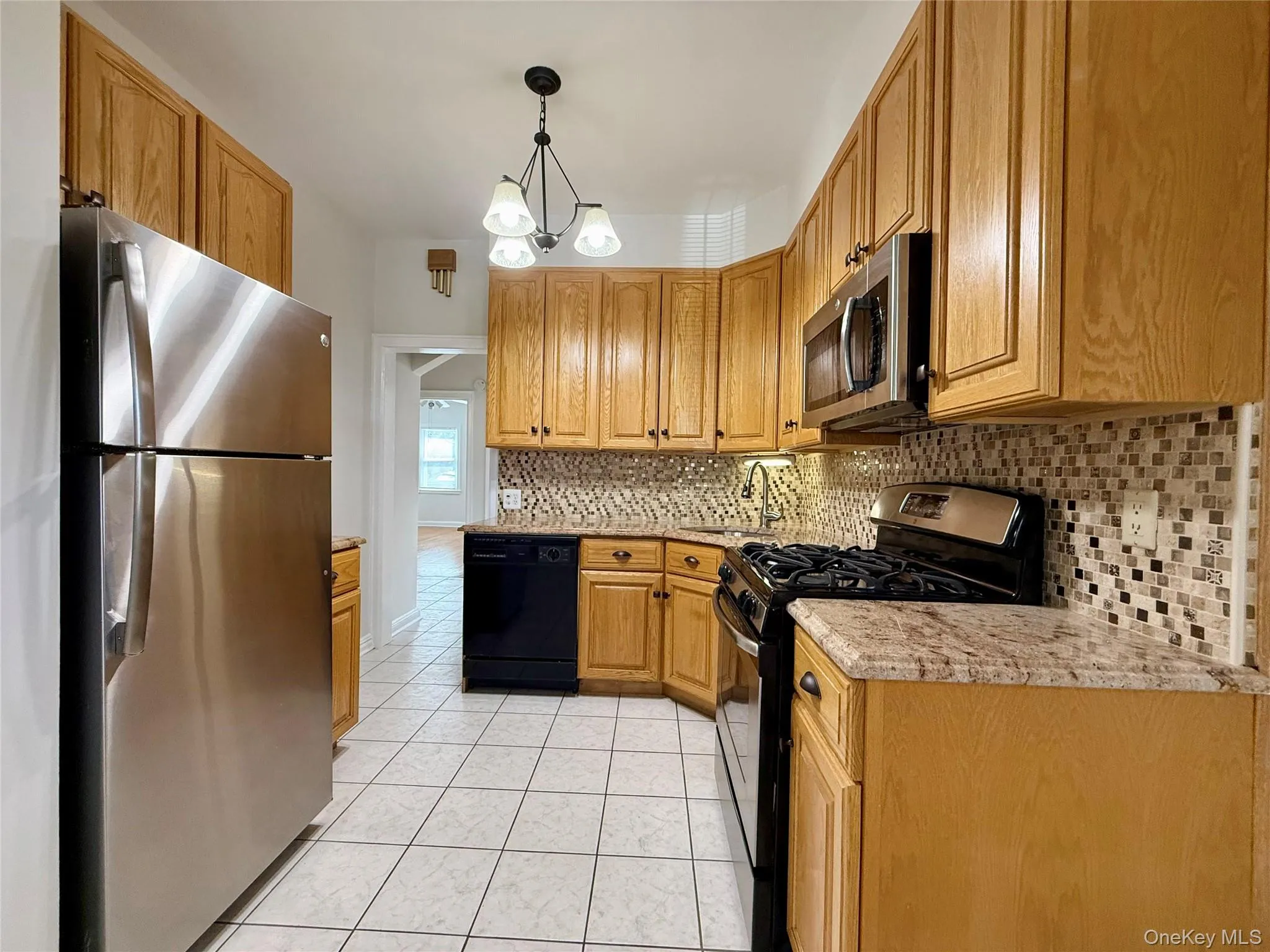 Kitchen featuring oak wood cabinetry, a mosaic tile backsplash, and a ceramic tile floor Kitchen featuring oak wood cabinetry, a mosaic tile backsplash, and a ceramic tile floor