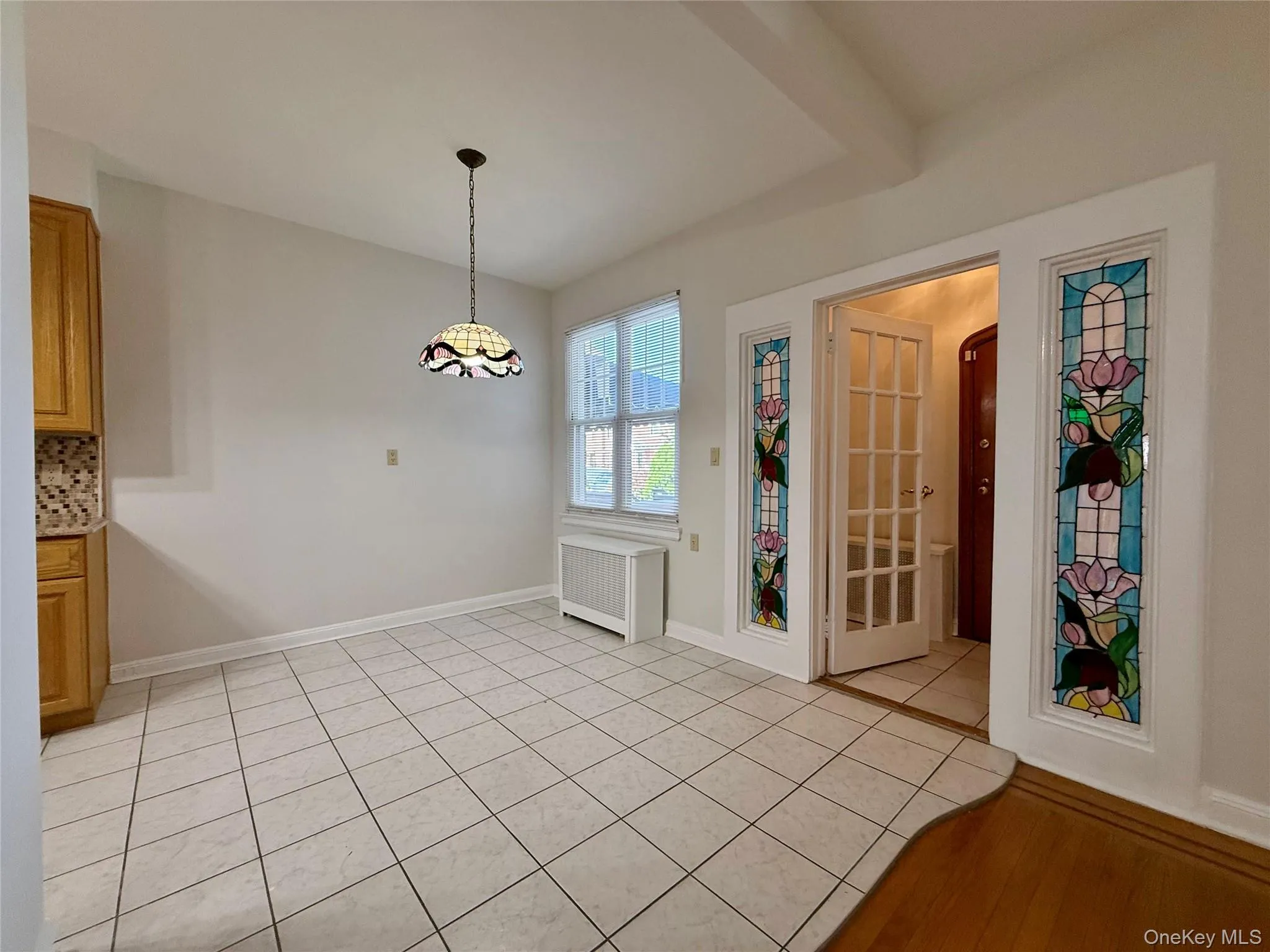 Dining area featuring a decorative tiffany style pendant light fixture, tiled flooring, and a window Dining area featuring a decorative tiffany style pendant light fixture, tiled flooring, and a window