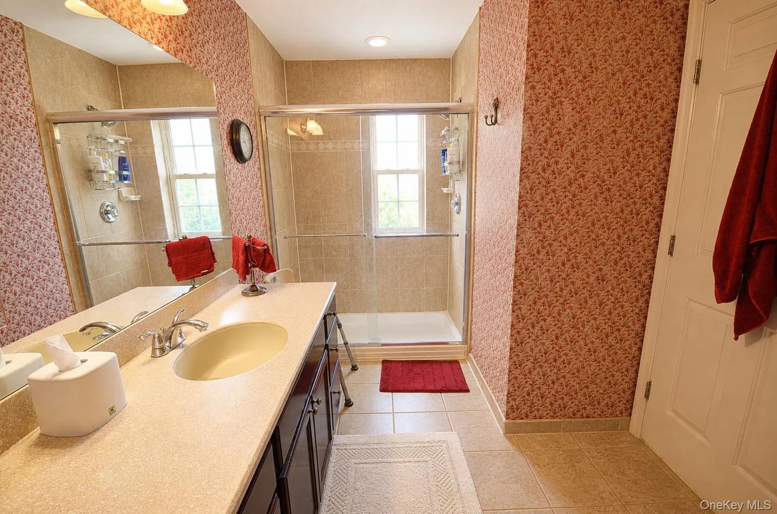 Bathroom featuring a double vanity with light-toned countertop, dark wood-finish cabinetry, and an integrated rectangular sink Bathroom featuring a double vanity with light-toned countertop, dark wood-finish cabinetry, and an integrated rectangular sink
