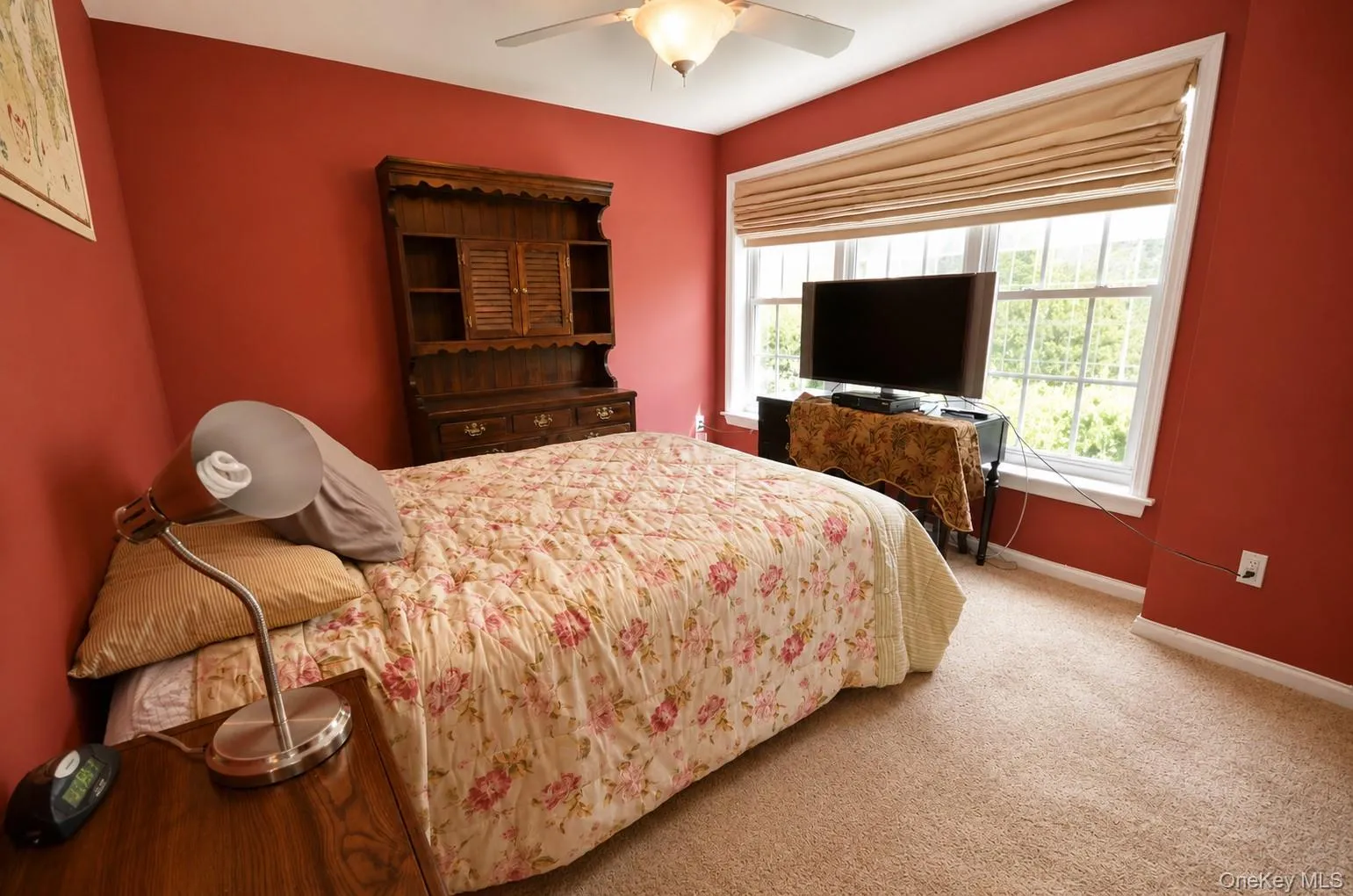 Room featuring carpeting, a ceiling fan, and a large window with Roman shades Room featuring carpeting, a ceiling fan, and a large window with Roman shades