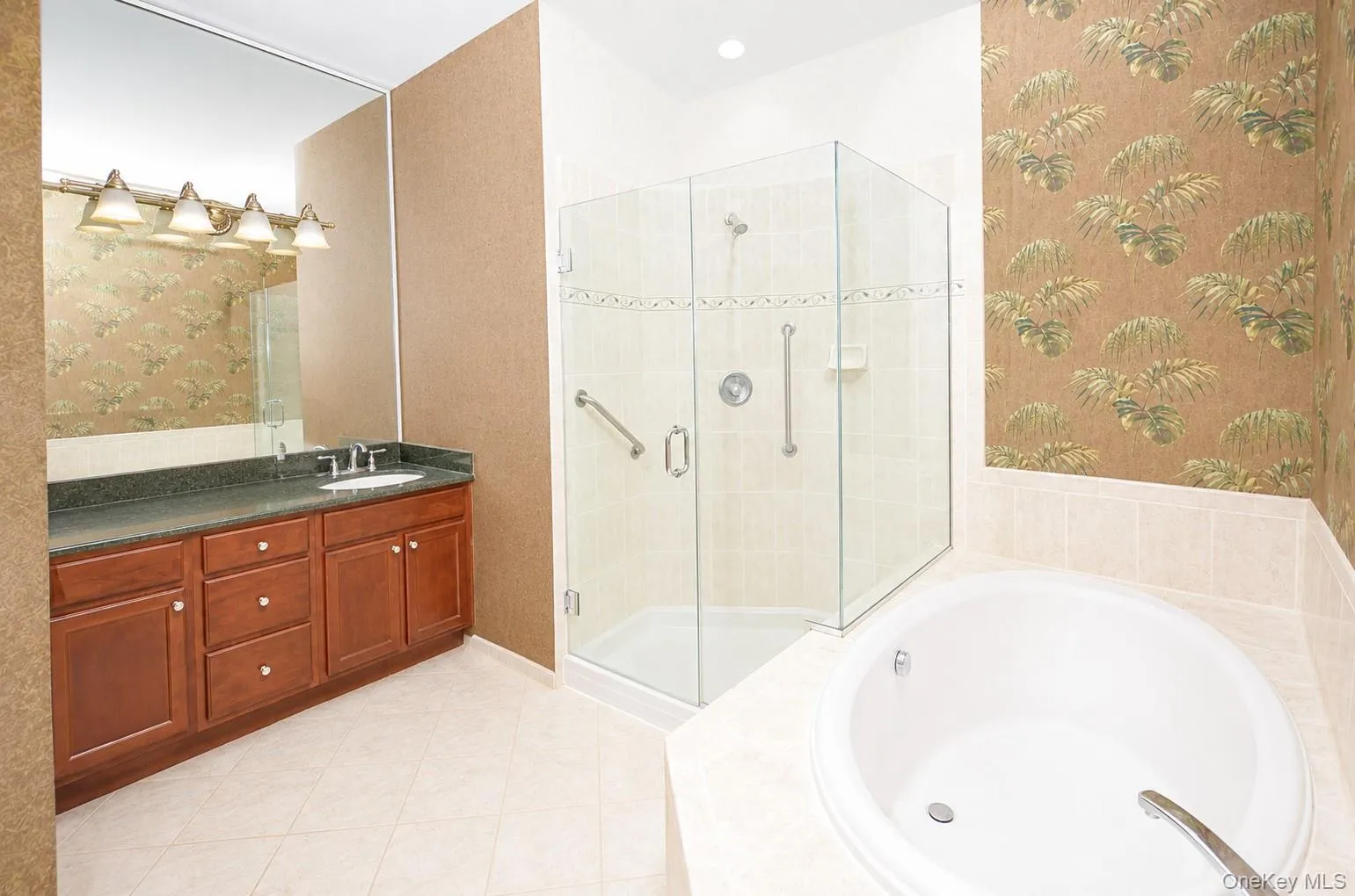 Bathroom featuring an integrated soaking tub, a glass-enclosed shower with tile surround, a wood-finish vanity with a dark countertop and undermount sink, and tile flooring Bathroom featuring an integrated soaking tub, a glass-enclosed shower with tile surround, a wood-finish vanity with a dark countertop and undermount sink, and tile flooring