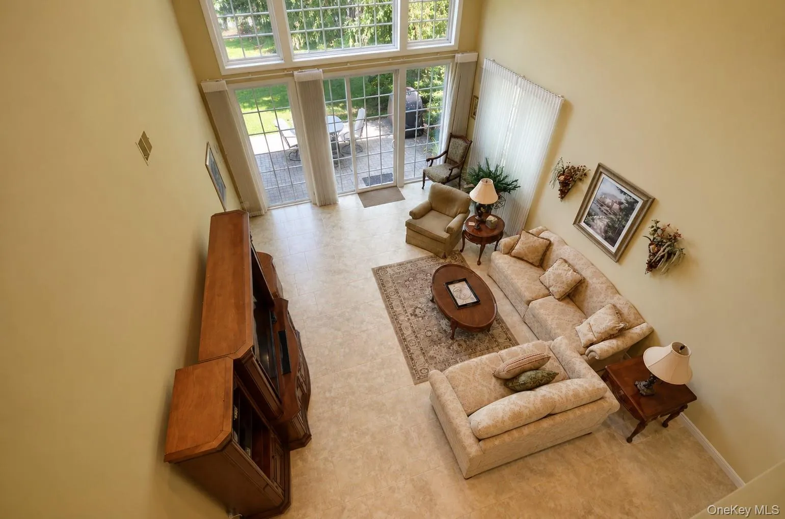 Two-story living area featuring tall windows and glass patio doors, a light-colored carpeted floor, and neutral wall paint Two-story living area featuring tall windows and glass patio doors, a light-colored carpeted floor, and neutral wall paint