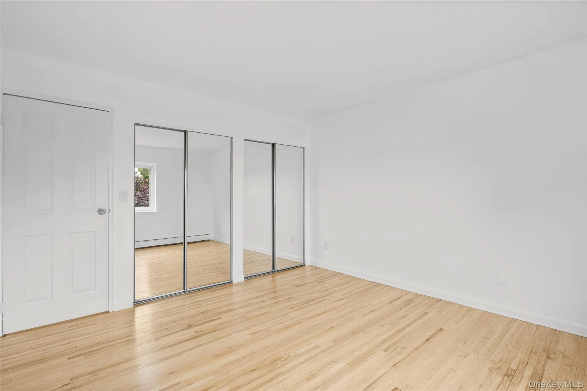 View of primary bedroom from corner of the room. Featuring mirrored double closets. View of primary bedroom from corner of the room. Featuring mirrored double closets.