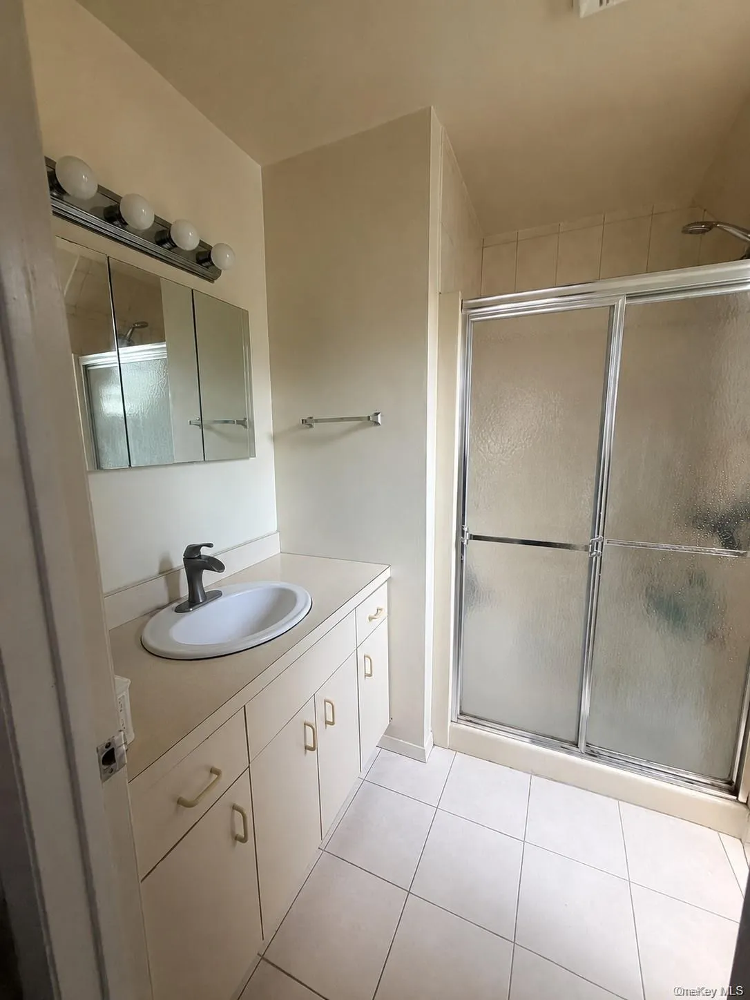 Bathroom featuring a shower with sliding glass doors, a vanity with an integrated sink, and a chrome faucet Bathroom featuring a shower with sliding glass doors, a vanity with an integrated sink, and a chrome faucet