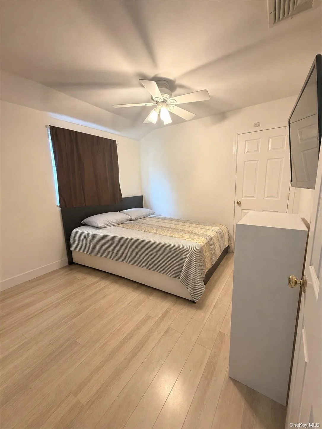Bright room featuring wood-finish flooring, a white ceiling fan, and white walls Bright room featuring wood-finish flooring, a white ceiling fan, and white walls