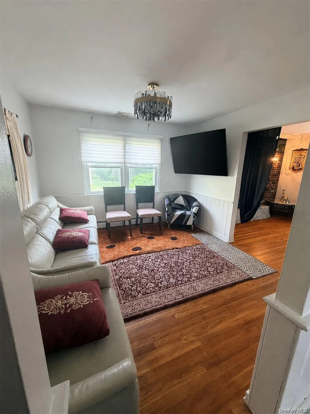 Wood-finish flooring with white wainscoting and a modern semi-flush mount light fixture Wood-finish flooring with white wainscoting and a modern semi-flush mount light fixture