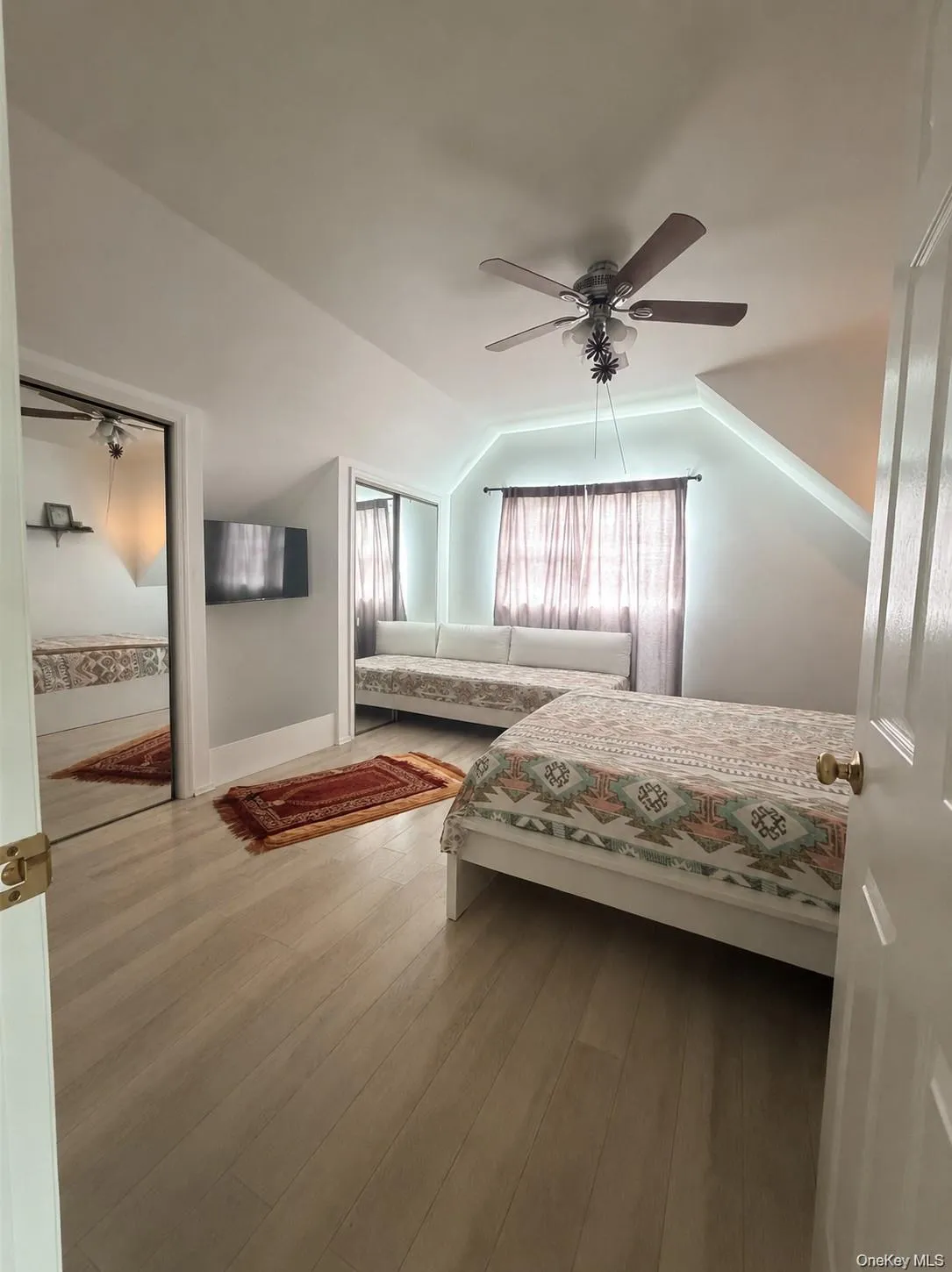 Bright room featuring a sloped ceiling with a ceiling fan Bright room featuring a sloped ceiling with a ceiling fan