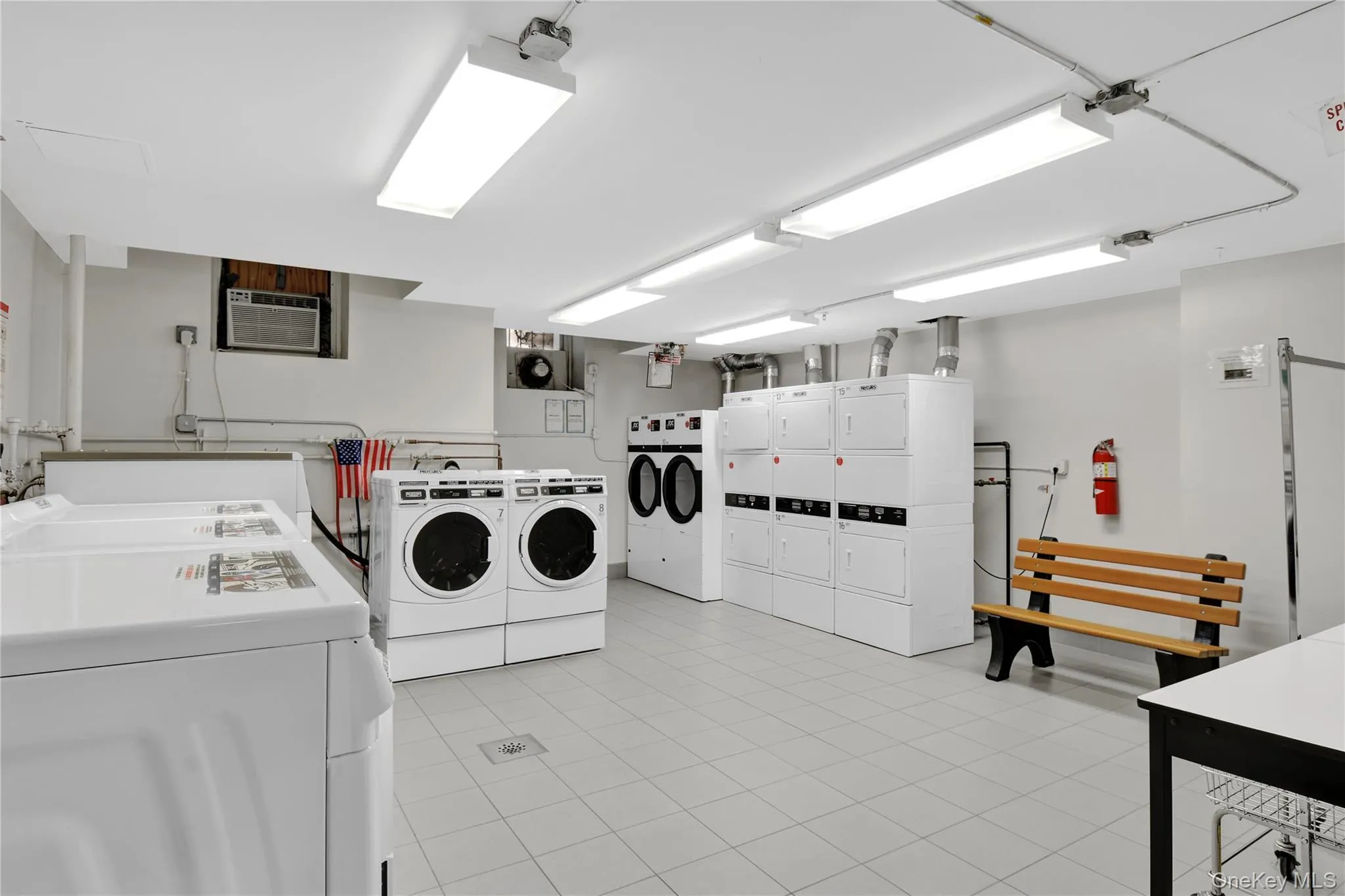 Shared laundry room with separate washer and dryer, light tile patterned flooring, and an AC wall unit Shared laundry room with separate washer and dryer, light tile patterned flooring, and an AC wall unit