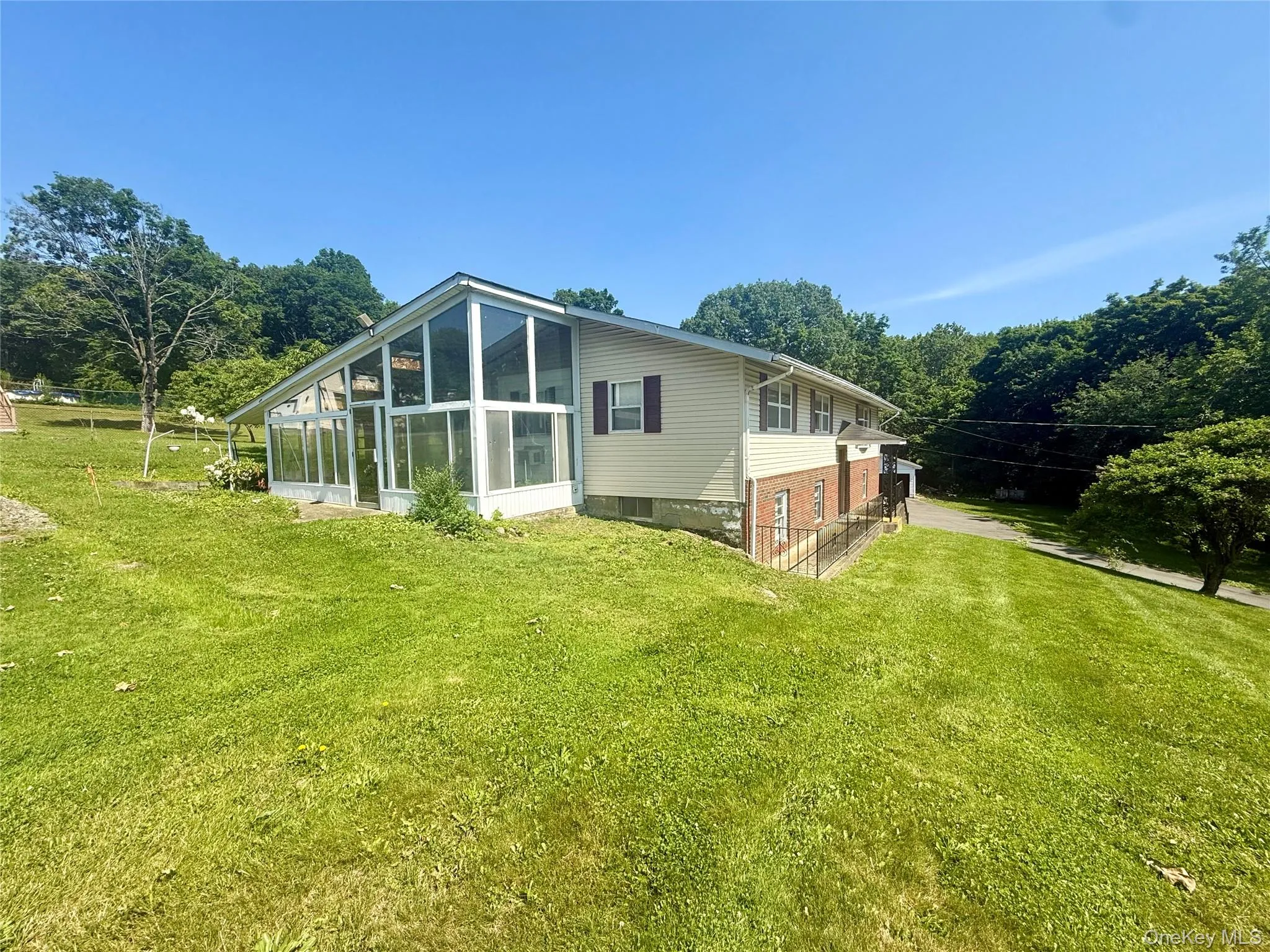 Rear view of property with a sunroom and a lawn Rear view of property with a sunroom and a lawn