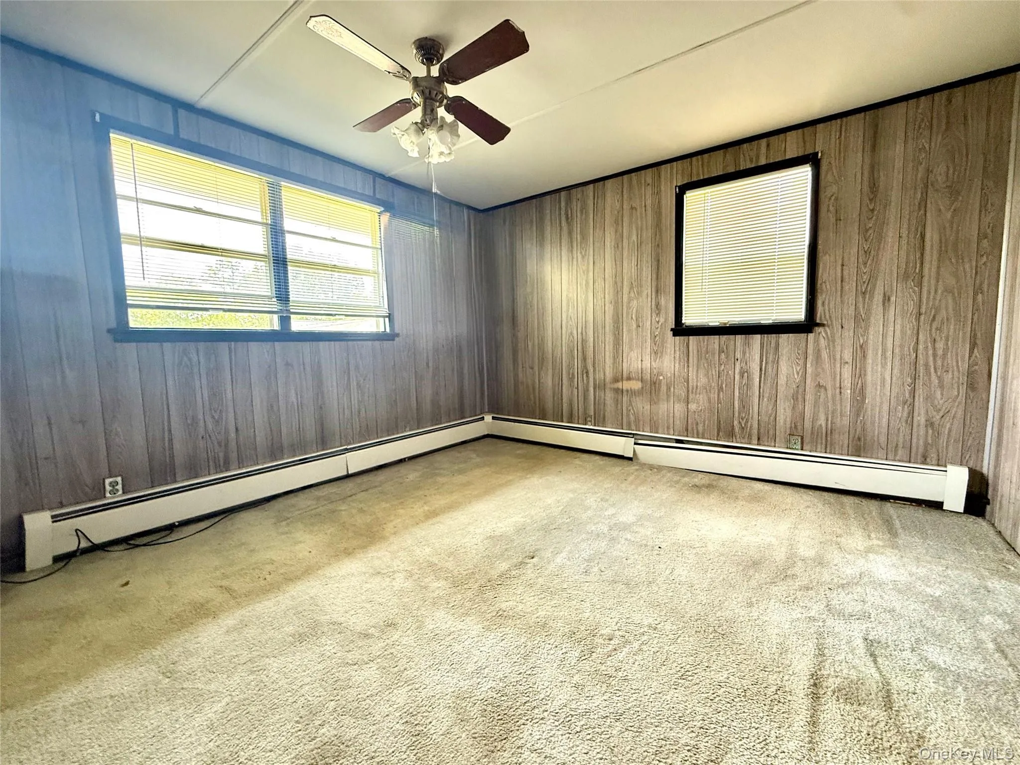 Carpeted empty room with ceiling fan and wood walls Carpeted empty room with ceiling fan and wood walls