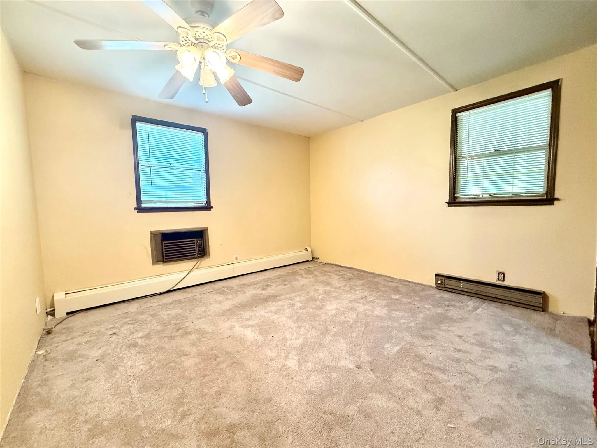 Carpeted spare room with a baseboard heating unit and ceiling fan Carpeted spare room with a baseboard heating unit and ceiling fan
