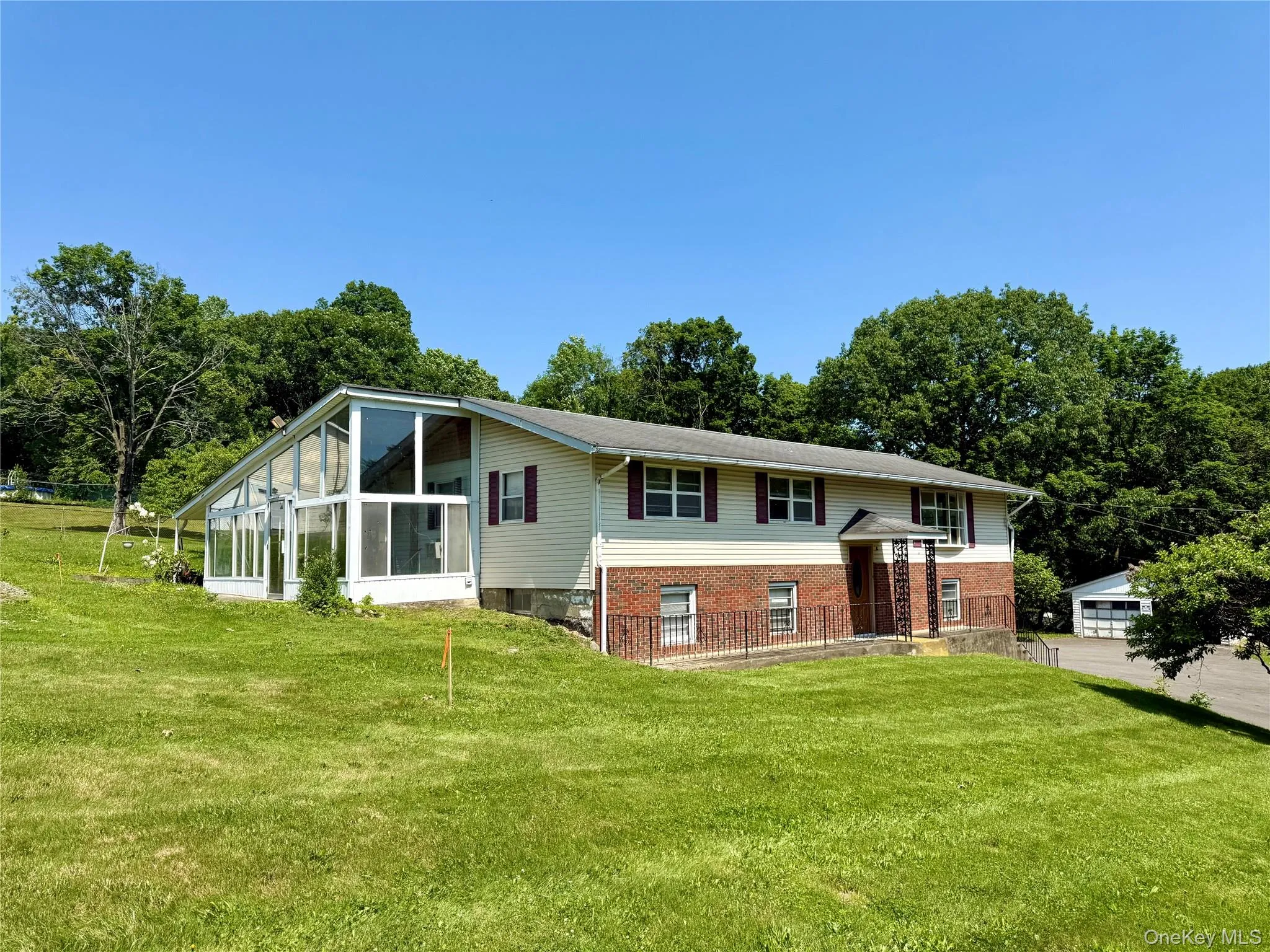 Bi-level home with a front yard, a sunroom, and brick siding Bi-level home with a front yard, a sunroom, and brick siding