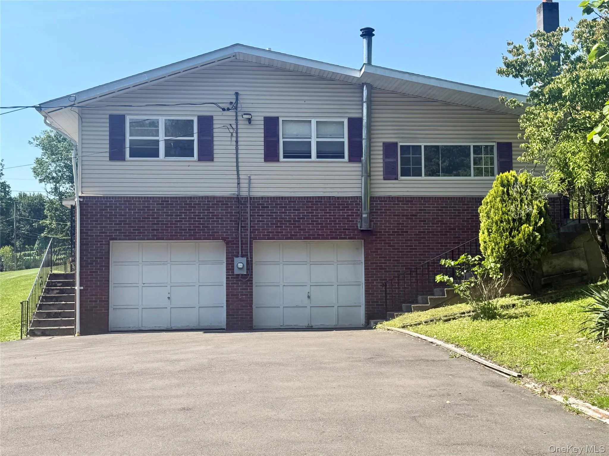 View of side of home featuring stairs, brick siding, asphalt driveway, and a garage View of side of home featuring stairs, brick siding, asphalt driveway, and a garage