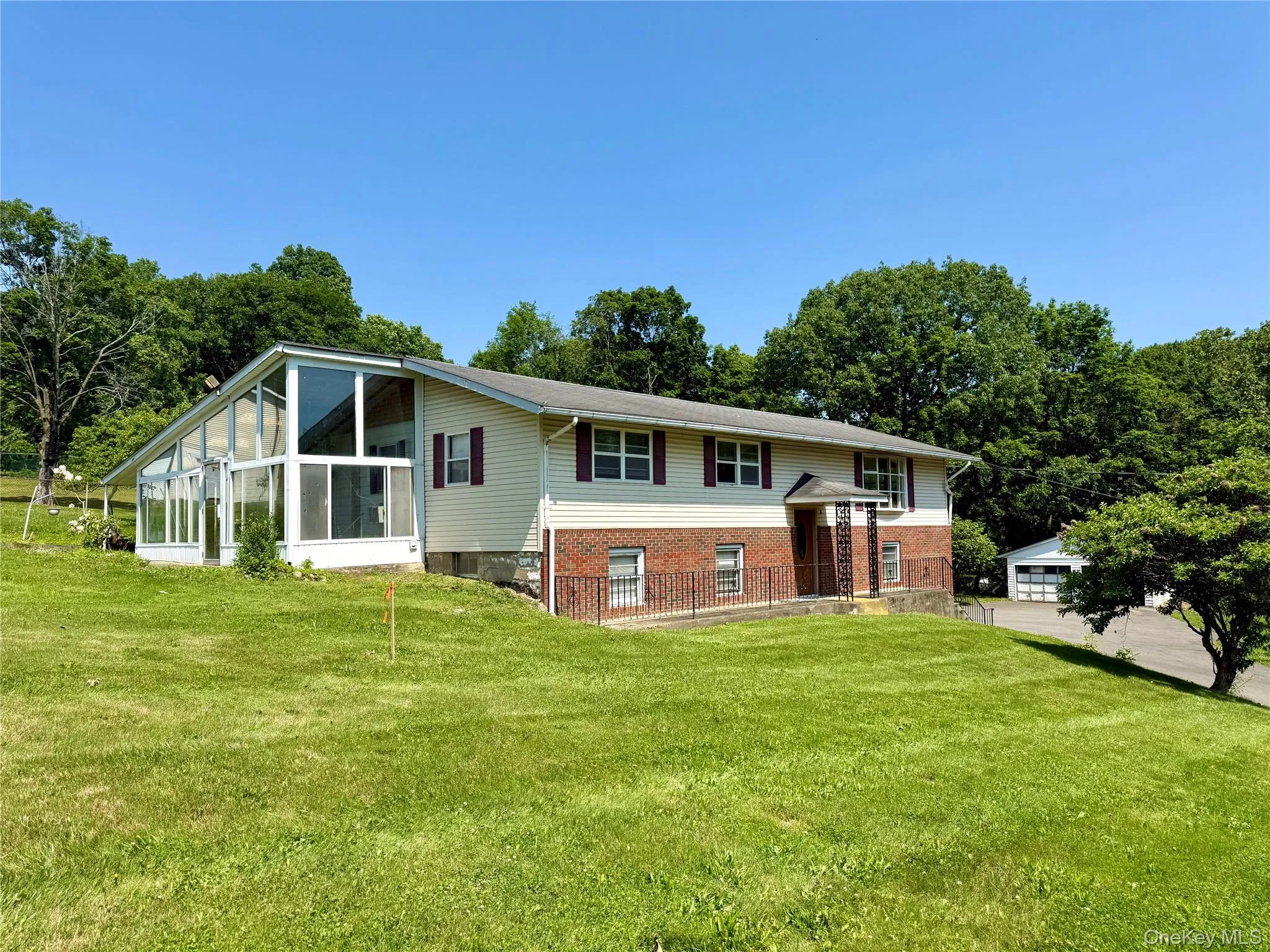 Raised ranch with a sunroom, a front lawn, and brick siding Raised ranch with a sunroom, a front lawn, and brick siding