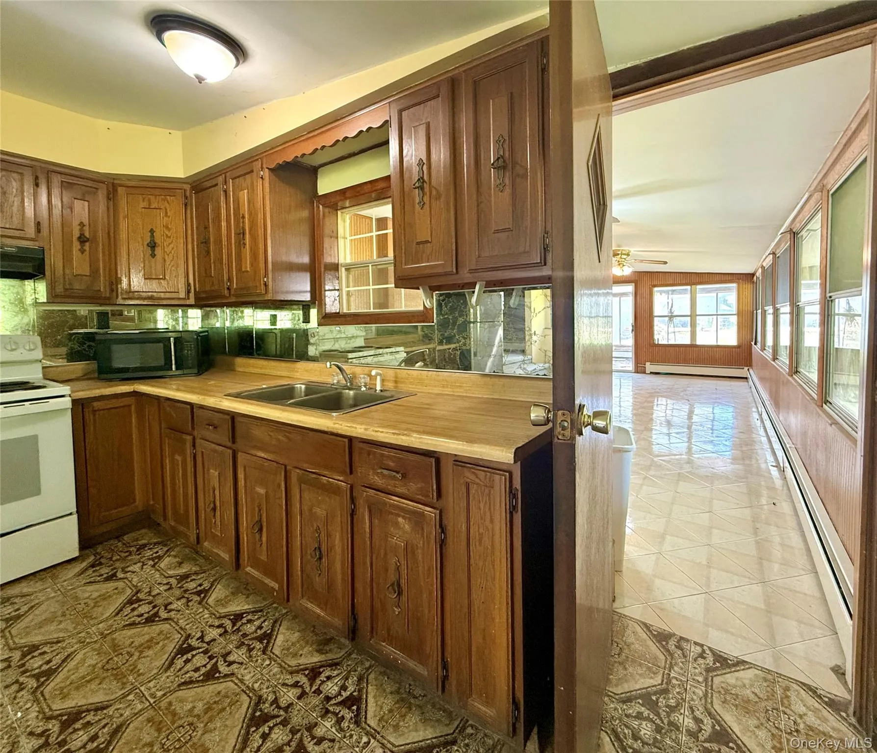 Kitchen featuring white electric stove, black microwave, a sink, and tasteful backsplash Kitchen featuring white electric stove, black microwave, a sink, and tasteful backsplash