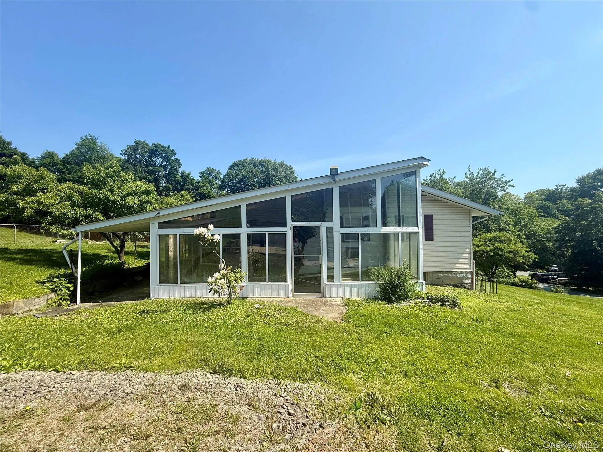 Rear view of property with a sunroom and a lawn Rear view of property with a sunroom and a lawn