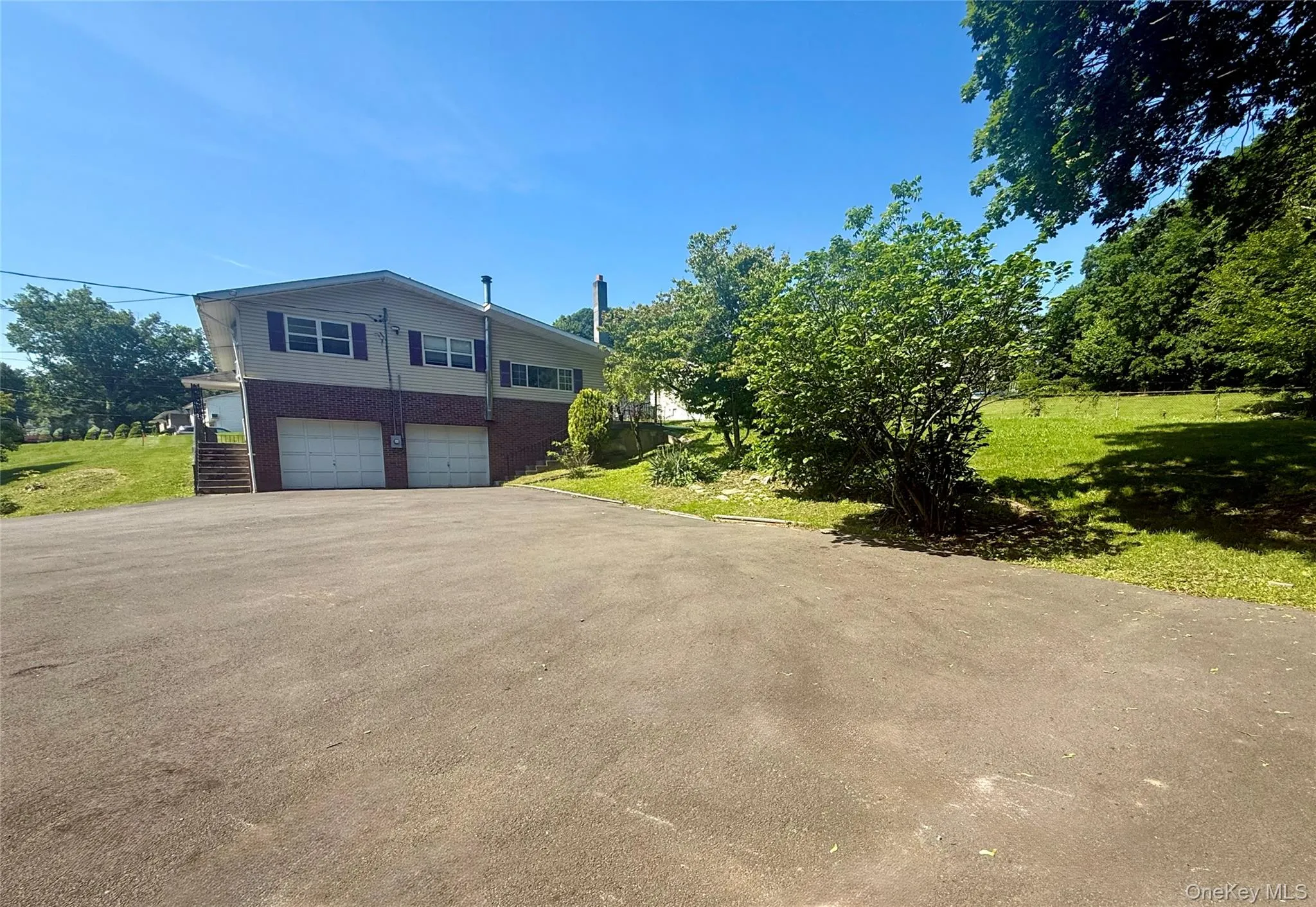 View of side of property with asphalt driveway, a garage, and a yard View of side of property with asphalt driveway, a garage, and a yard