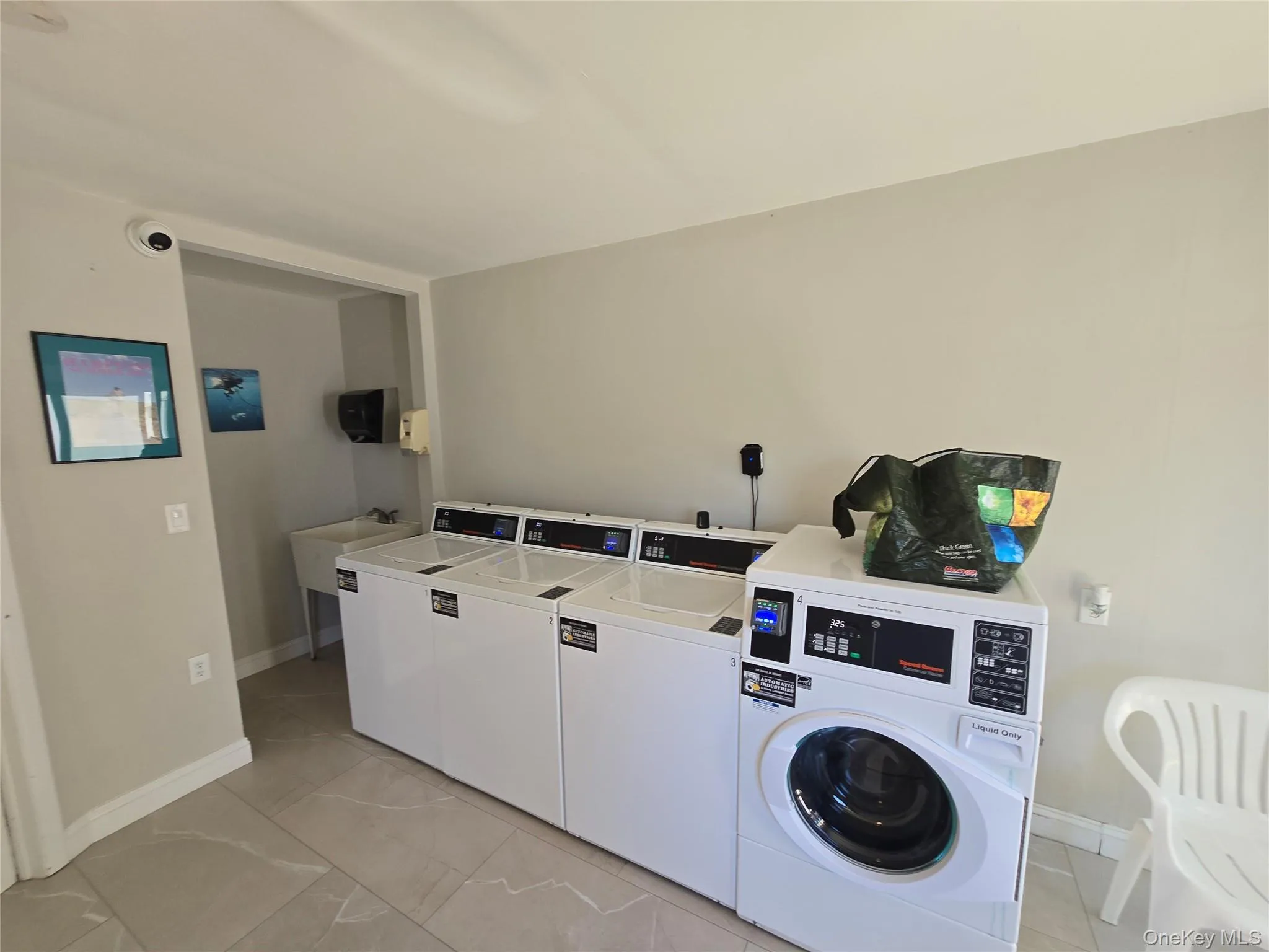 Dedicated laundry facility featuring multiple white washing machines and dryers Dedicated laundry facility featuring multiple white washing machines and dryers