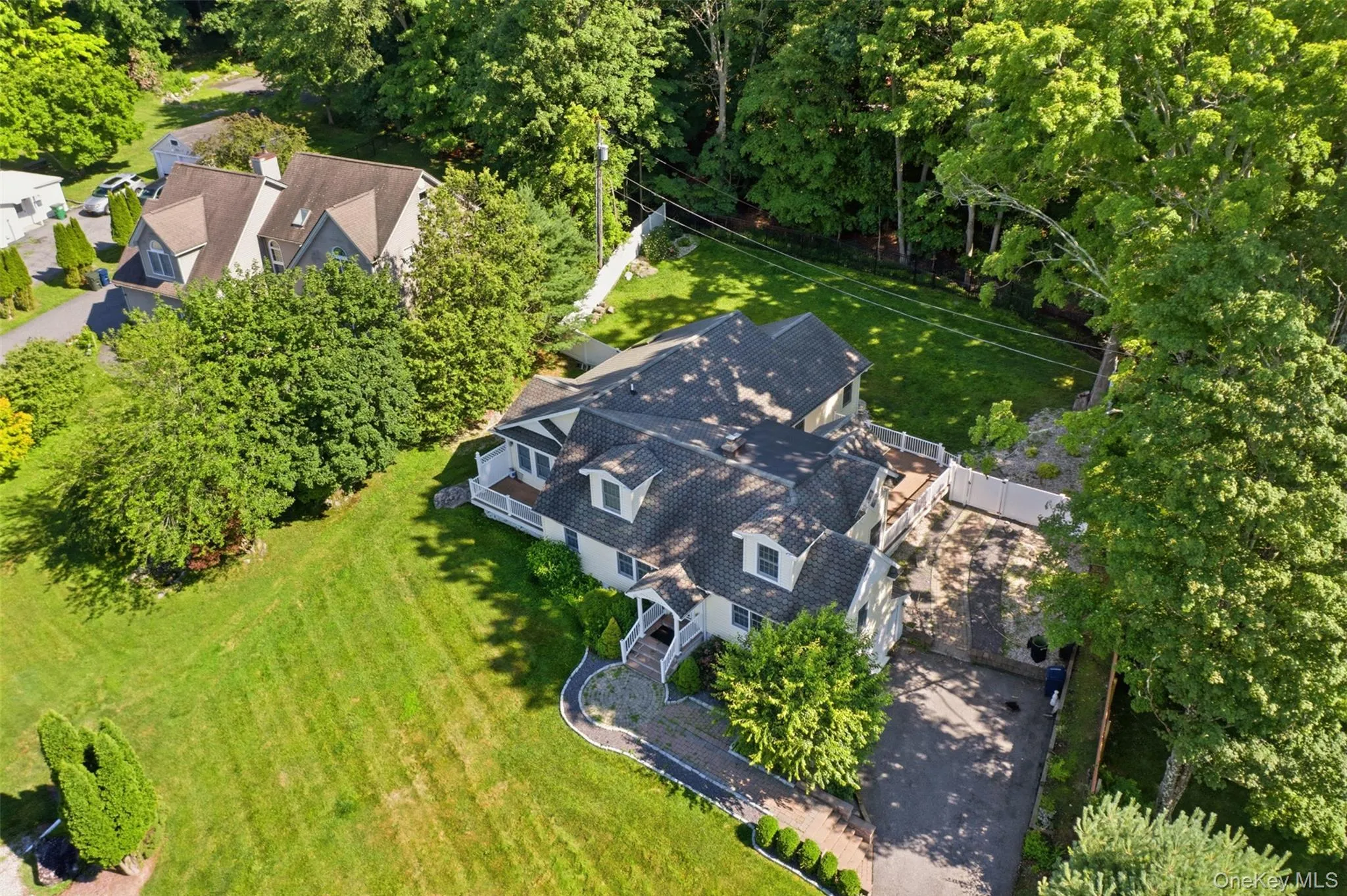 Expansive aerial perspective showcasing a residential property with a multi-level deck, a paved driveway, and mature landscaping Expansive aerial perspective showcasing a residential property with a multi-level deck, a paved driveway, and mature landscaping