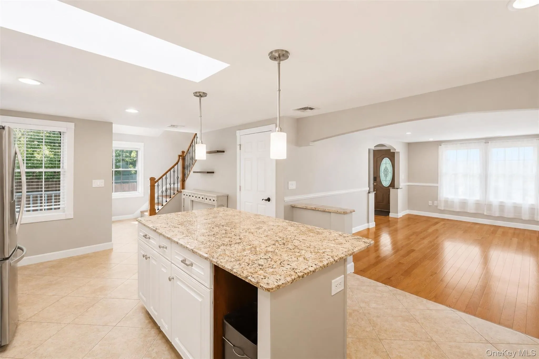 Central kitchen island with a light-toned granite countertop and white cabinetry Central kitchen island with a light-toned granite countertop and white cabinetry