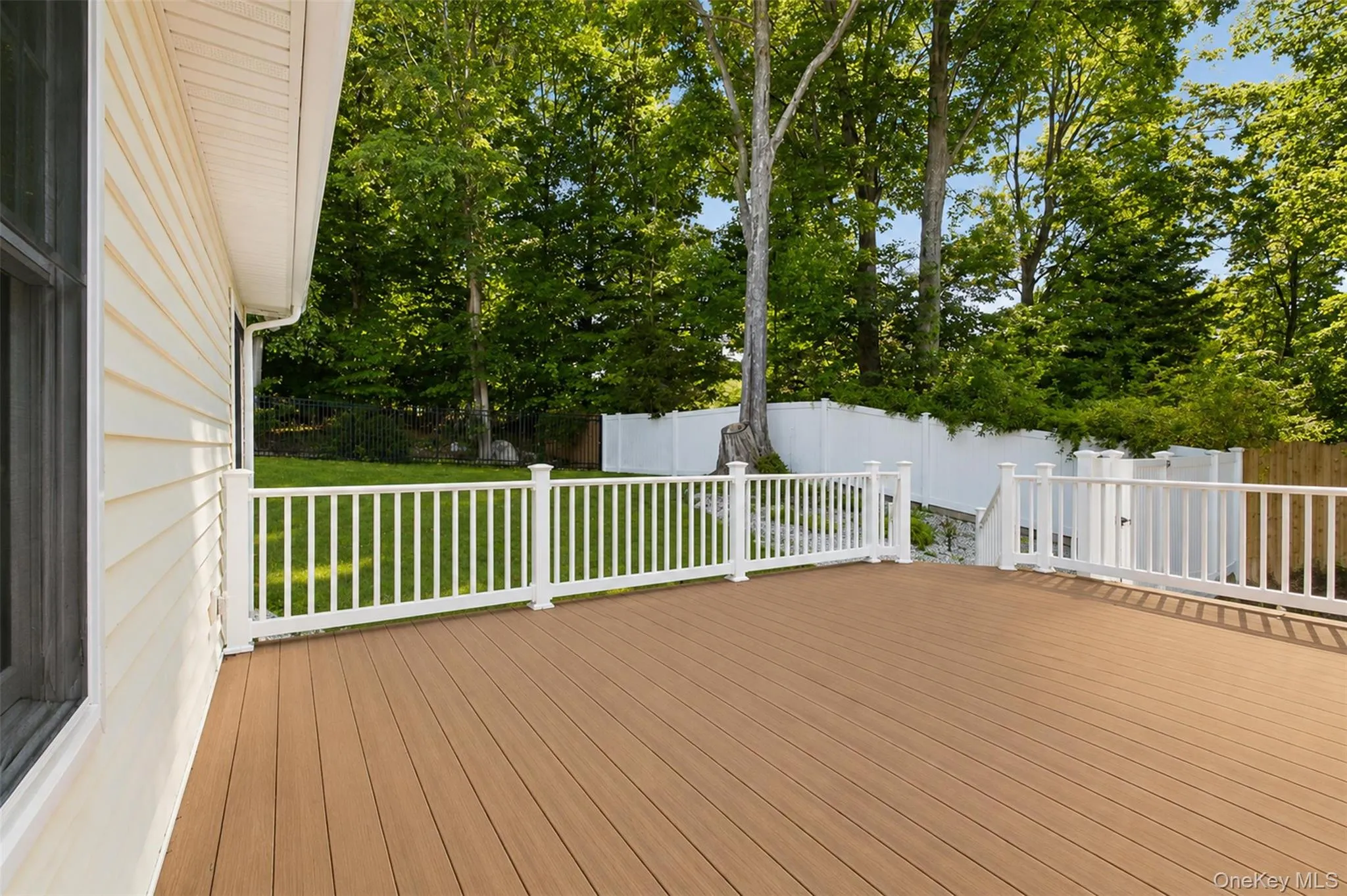 Expansive outdoor deck featuring wood-finish flooring and white railings Expansive outdoor deck featuring wood-finish flooring and white railings