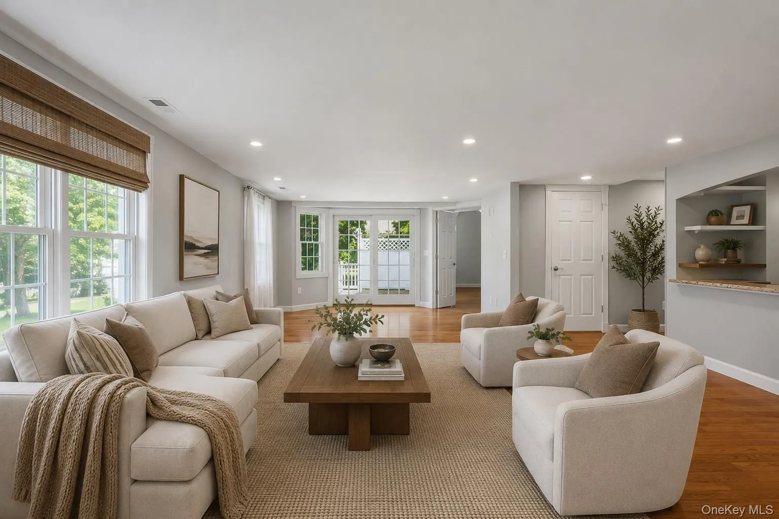 Spacious family room area featuring wood-finish flooring, recessed lighting, and a neutral color palette Spacious family room area featuring wood-finish flooring, recessed lighting, and a neutral color palette