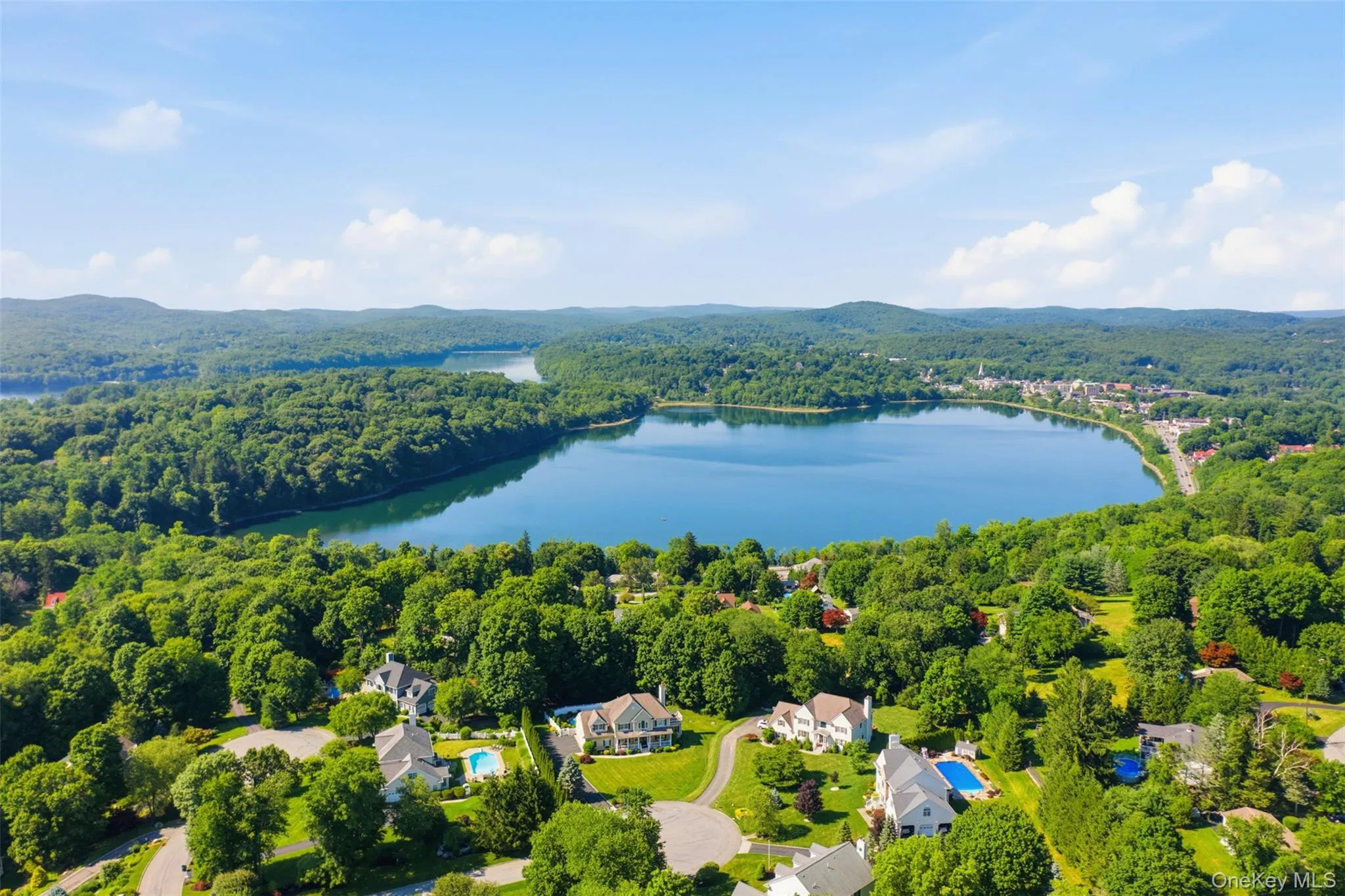 Aerial perspective showcasing a large body of water surrounded by expansive green landscapes and residential properties Aerial perspective showcasing a large body of water surrounded by expansive green landscapes and residential properties