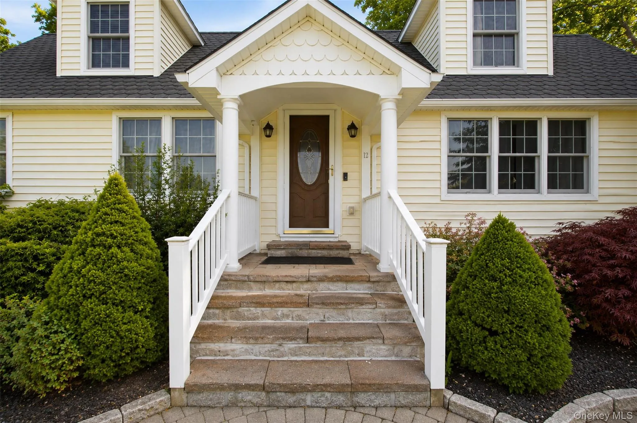 Siding exterior featuring a portico entry with white columns and railings Siding exterior featuring a portico entry with white columns and railings