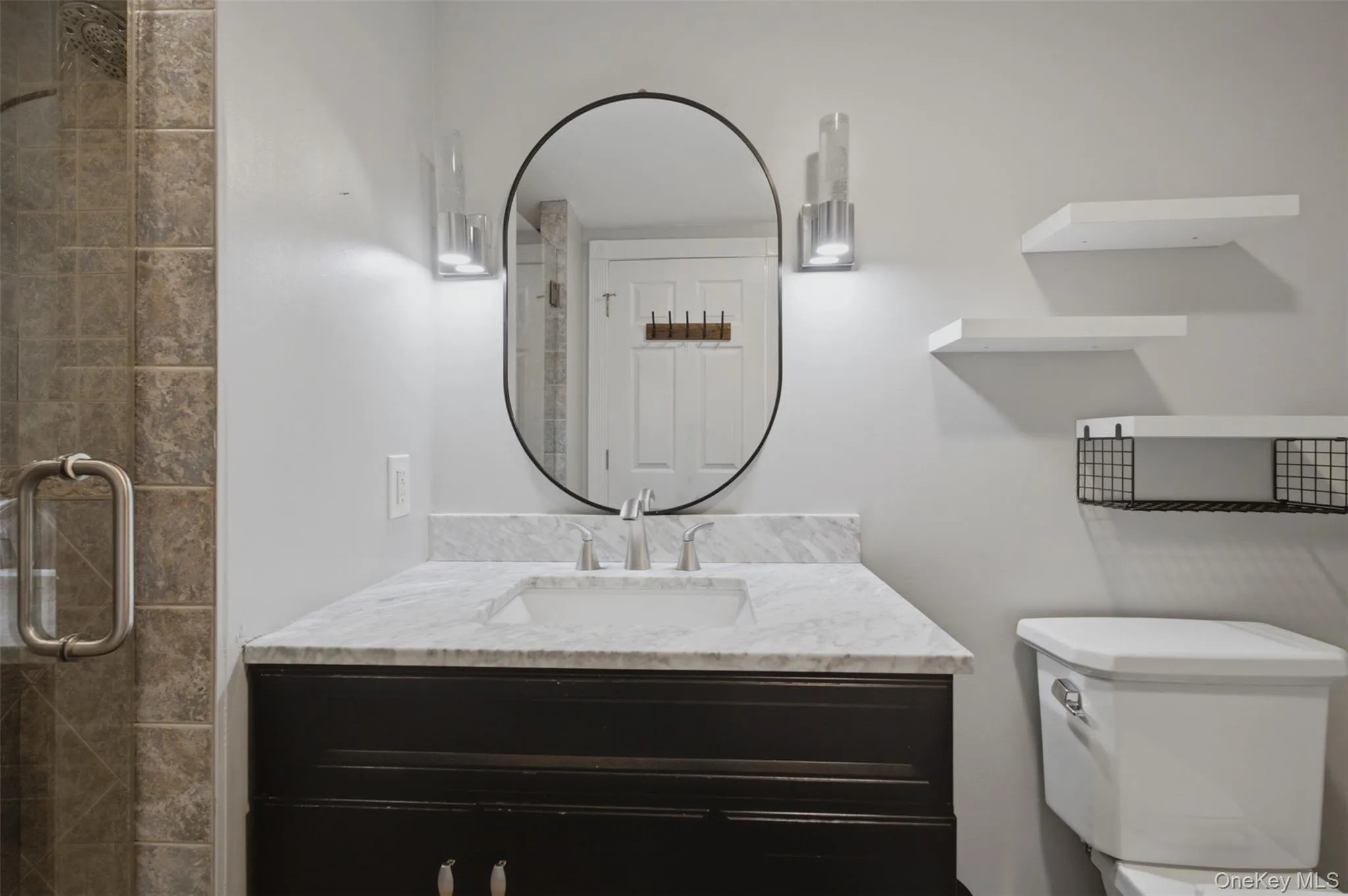 Bathroom vanity with a white marble countertop, undermount sink, and dark wood-finish cabinetry Bathroom vanity with a white marble countertop, undermount sink, and dark wood-finish cabinetry