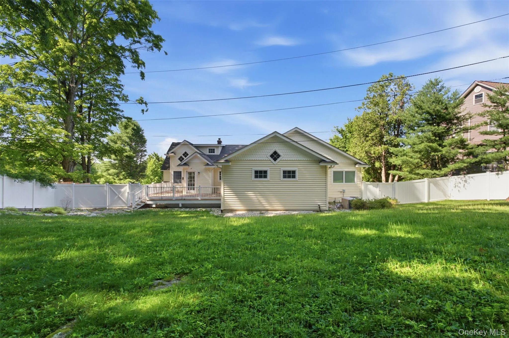Expansive lawn area featuring a white privacy fence Expansive lawn area featuring a white privacy fence