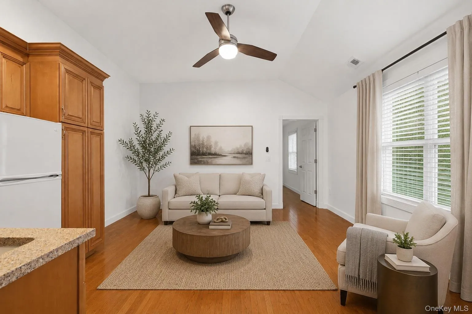 Open concept bonus room area featuring kitchenette wood-finish flooring, a vaulted ceiling, and a ceiling fan Open concept bonus room area featuring kitchenette wood-finish flooring, a vaulted ceiling, and a ceiling fan