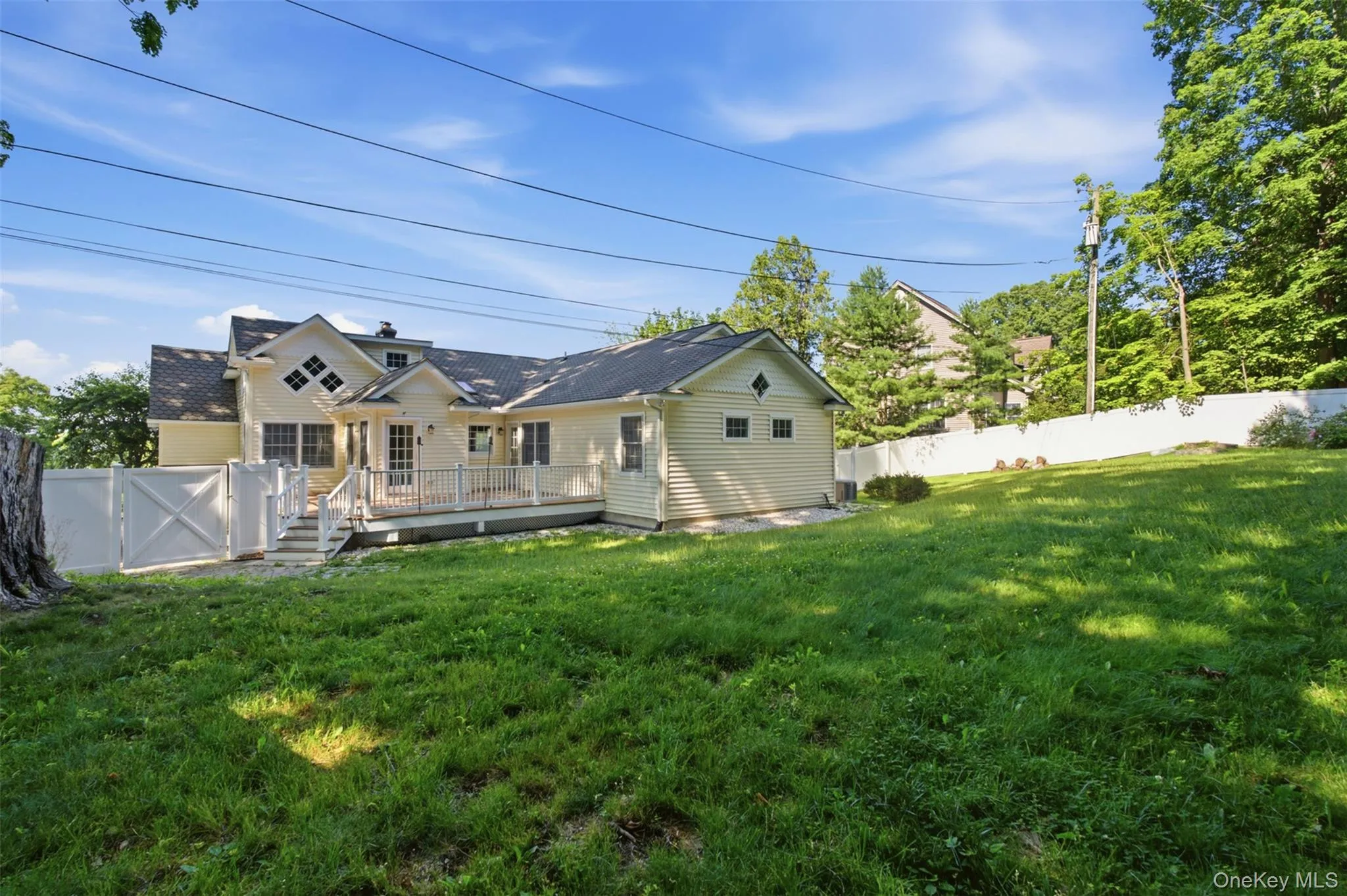 Expansive backyard featuring a manicured lawn, a full-length deck with white railings, and a privacy fence Expansive backyard featuring a manicured lawn, a full-length deck with white railings, and a privacy fence