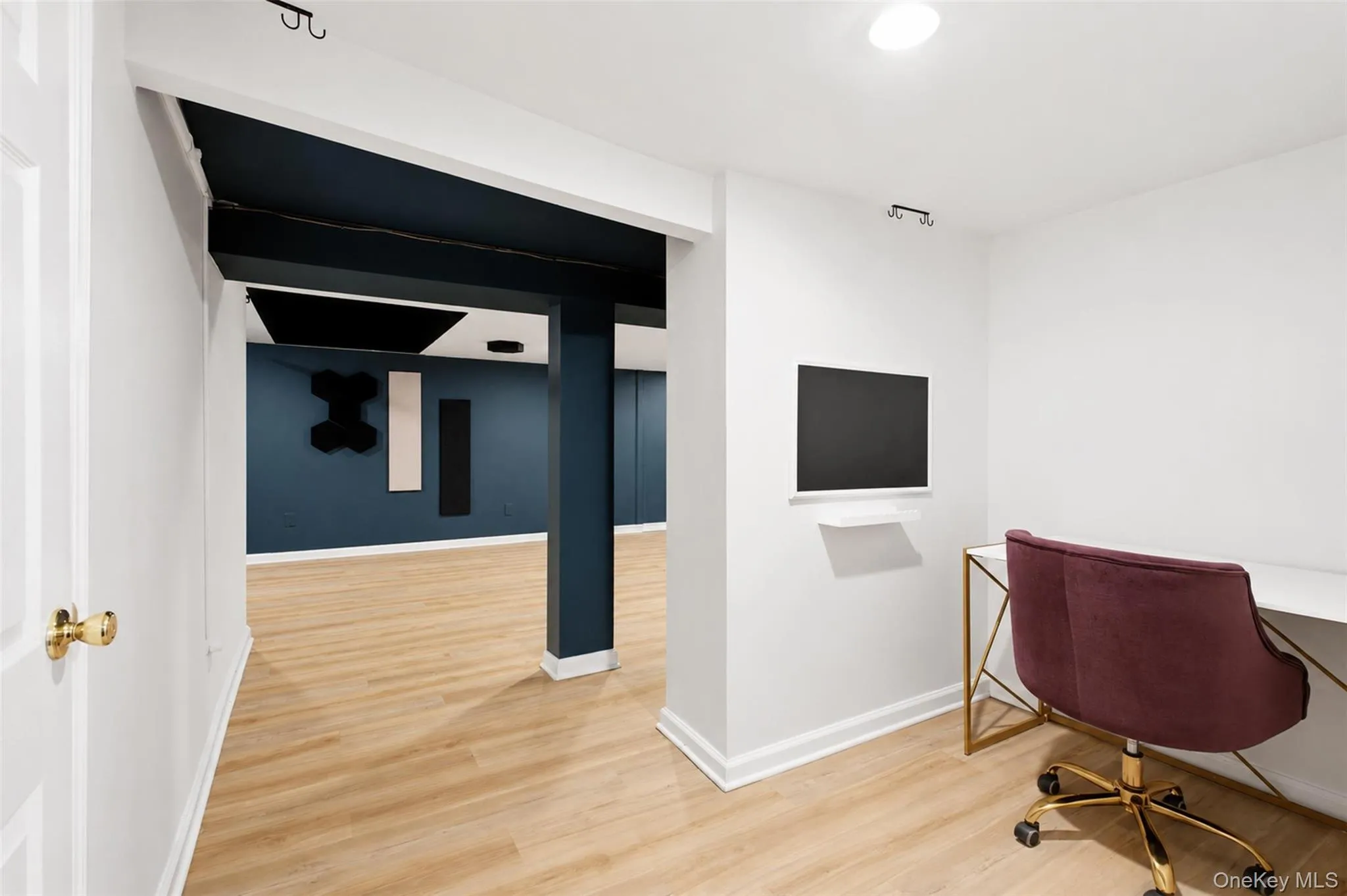 Versatile finished interior basement space featuring wood-finish flooring, recessed lighting, and a white wall-mounted monitor Versatile finished interior basement space featuring wood-finish flooring, recessed lighting, and a white wall-mounted monitor
