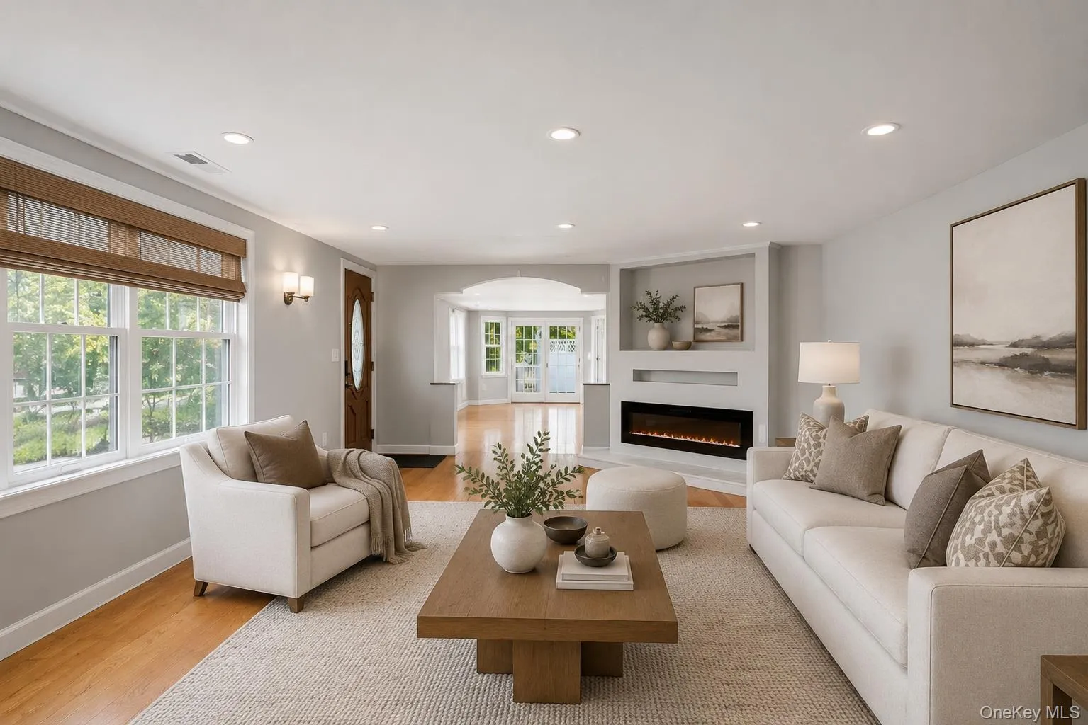 Bright living space featuring wood-finish flooring, recessed lighting, and an integrated electric fireplace with shelving above Bright living space featuring wood-finish flooring, recessed lighting, and an integrated electric fireplace with shelving above